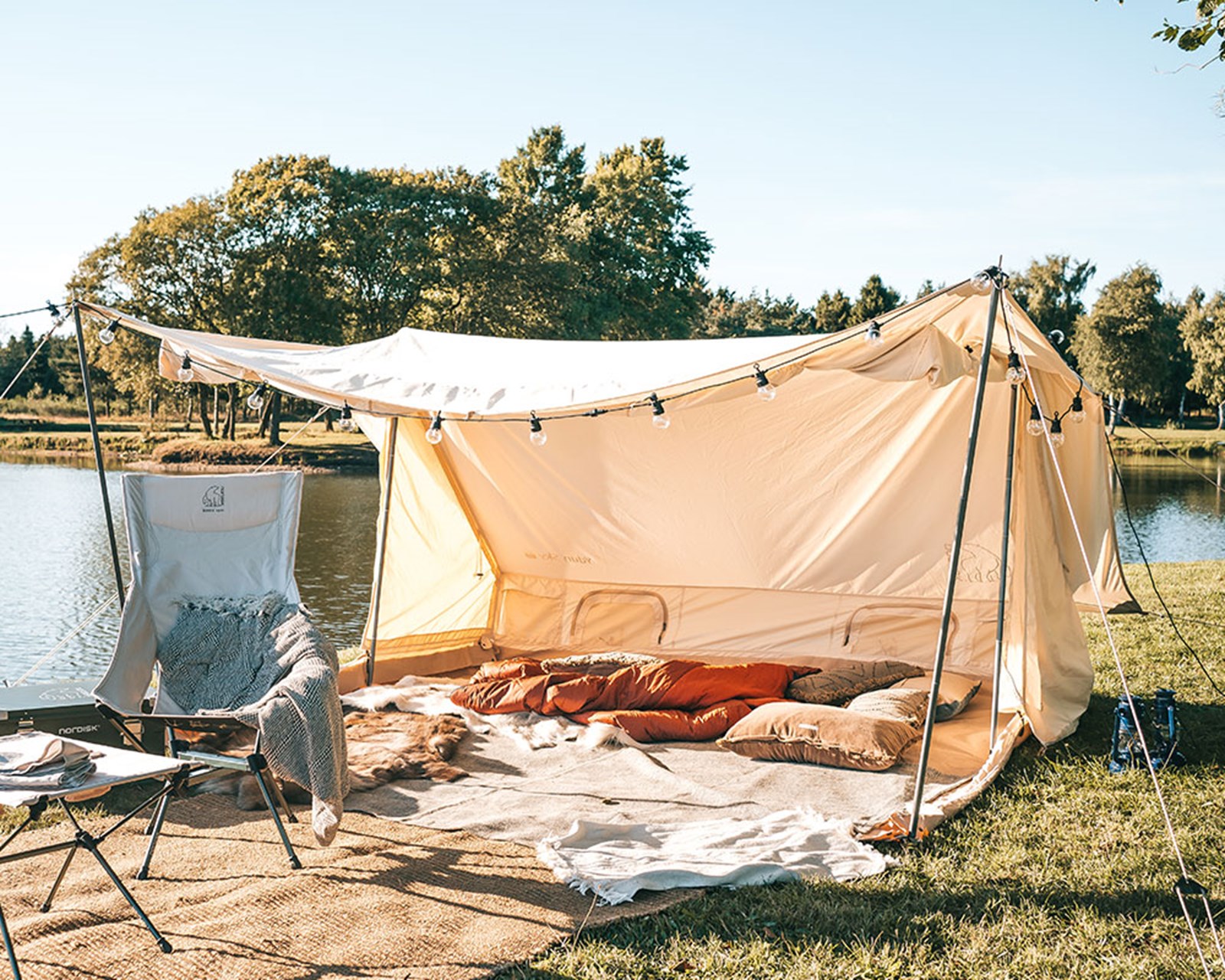 Glamping ved vandet med hyggelige puder og tæpper.
