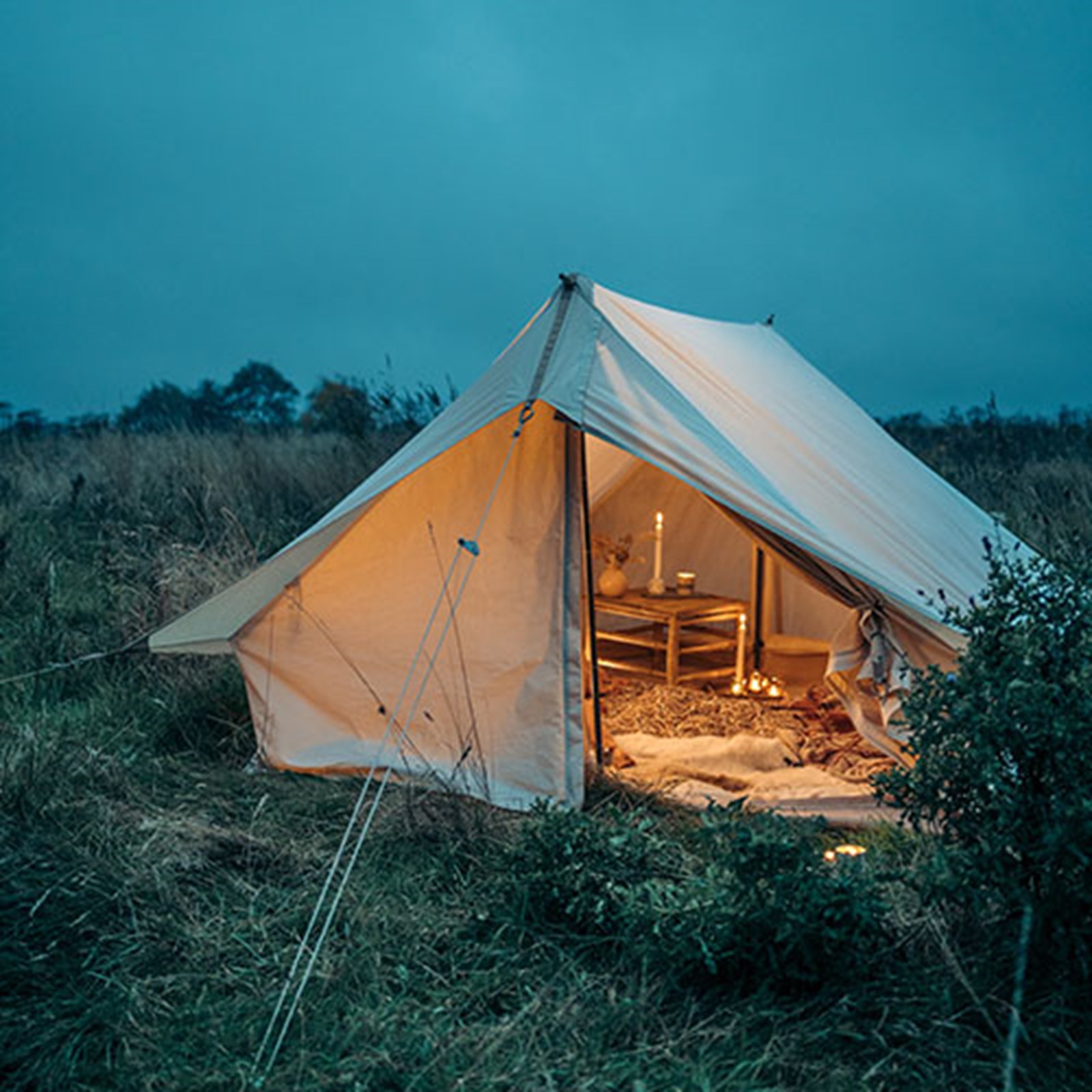 Et bomuldstelt med flot indretning og belysning i tusmørket.