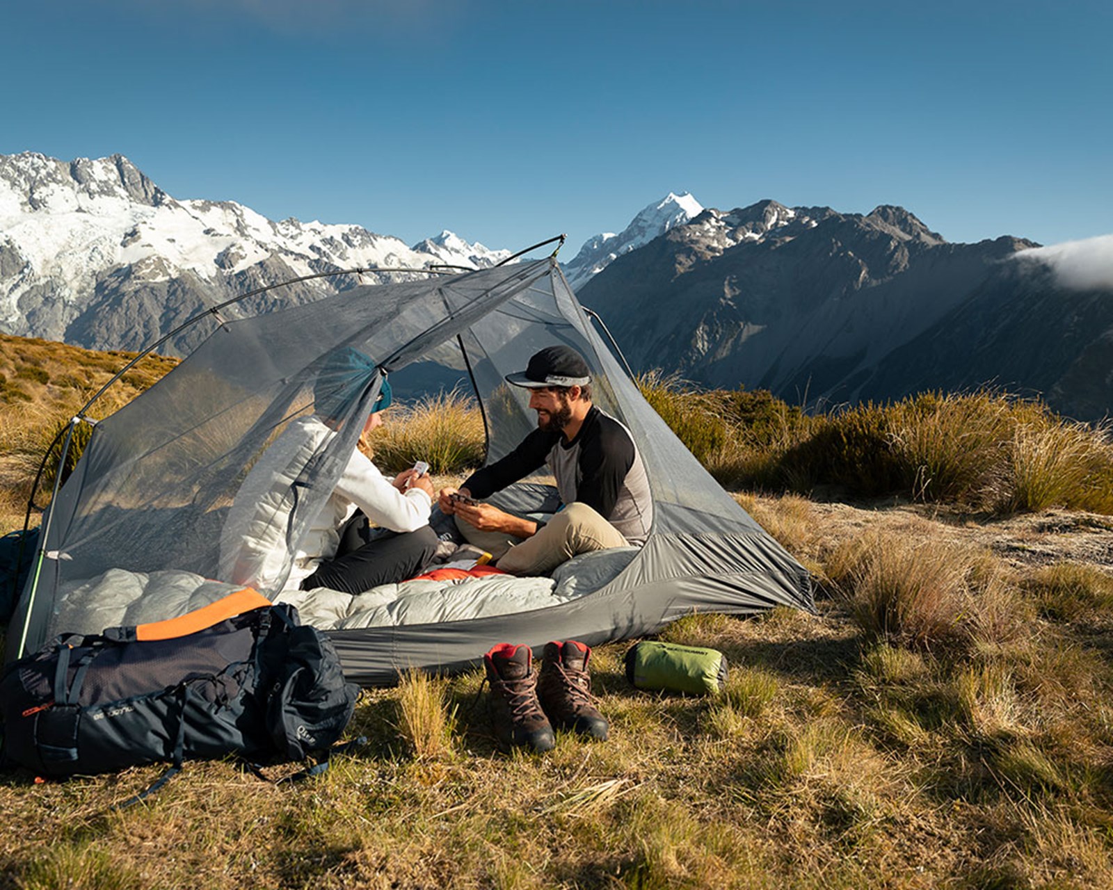 Par, der sidder i et telt uden oversejl og spiller kort.