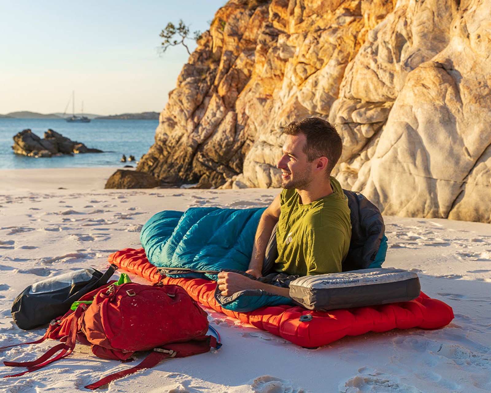 En mand der overnatter langs kysten på sit liggeunderlag.