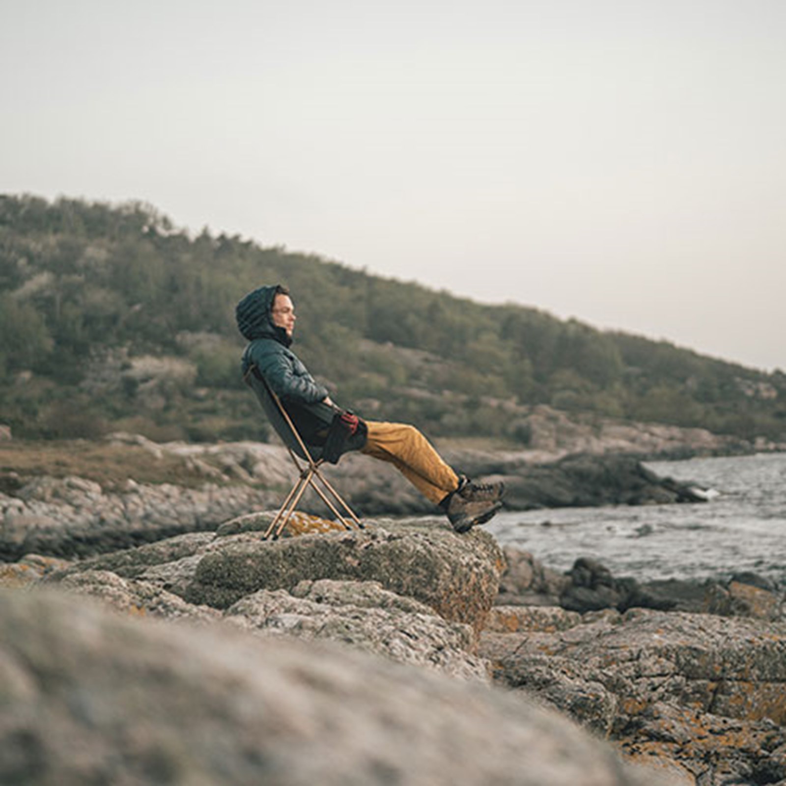 Person der sidder i en campingstol og kigger på havet.