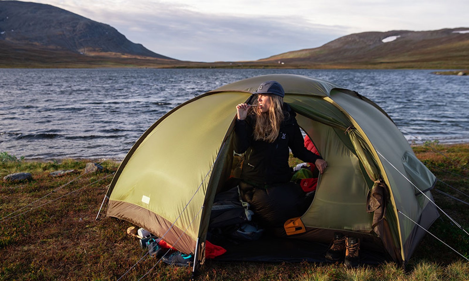 Person på telttur, der børster tænder uden for teltet.