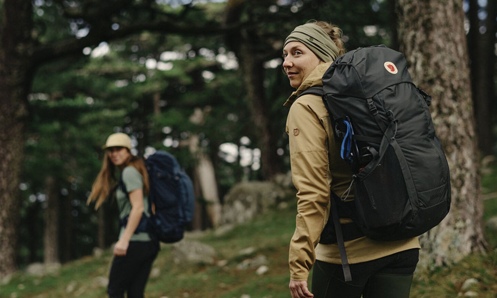 To kvinder på vandring i skoven med deres store vandrerygsække.