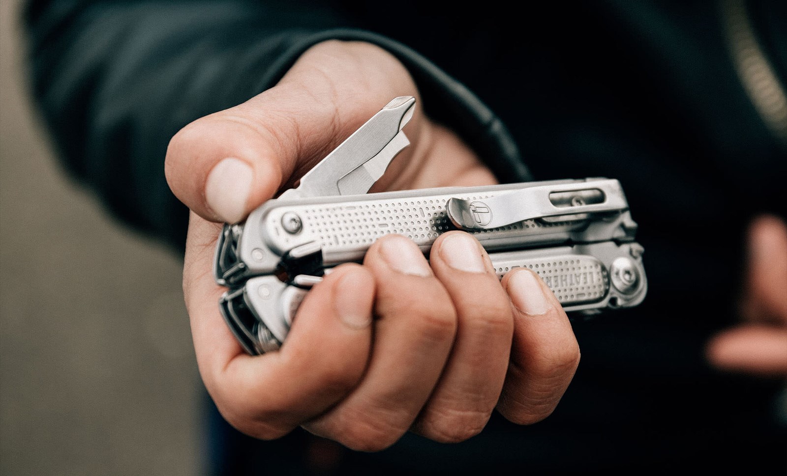 Person med et sammenfoldet multitool i hånden.
