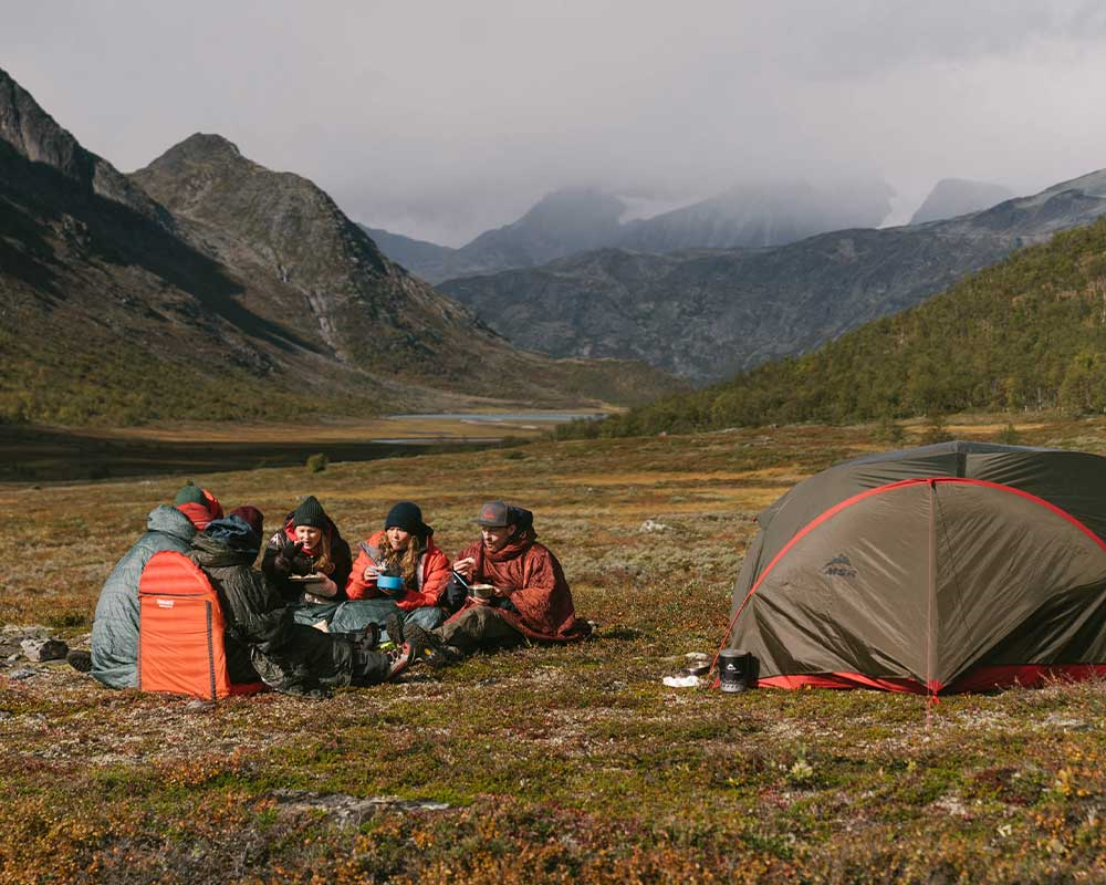 Gruppe friluftsflok der spiser ude i naturen