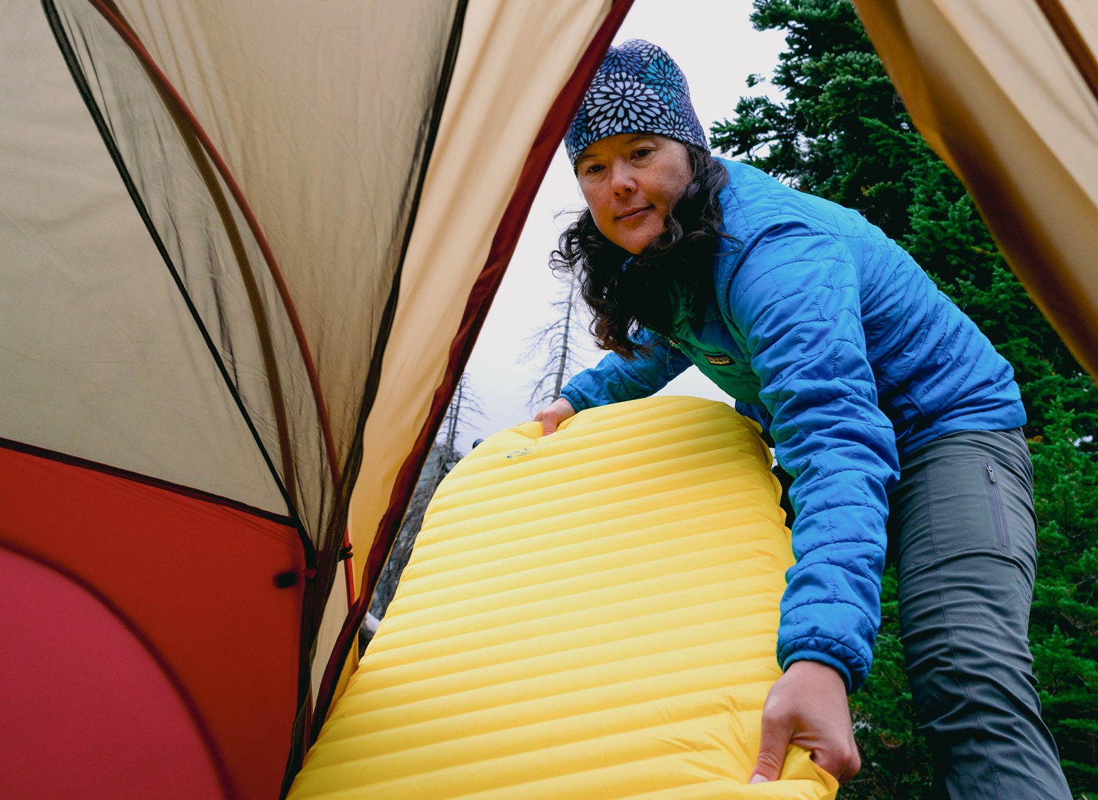 En kvinde der lægger sit liggeunderlag ind i et telt.
