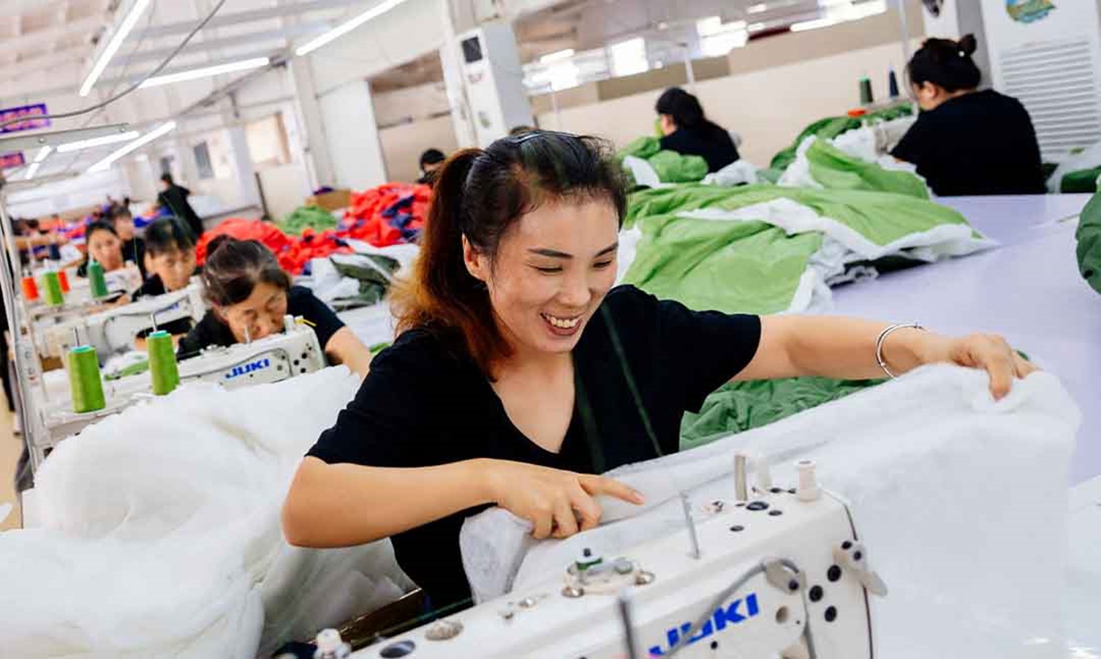 En glad kvinde der syer på en Cotopaxi fabrik.