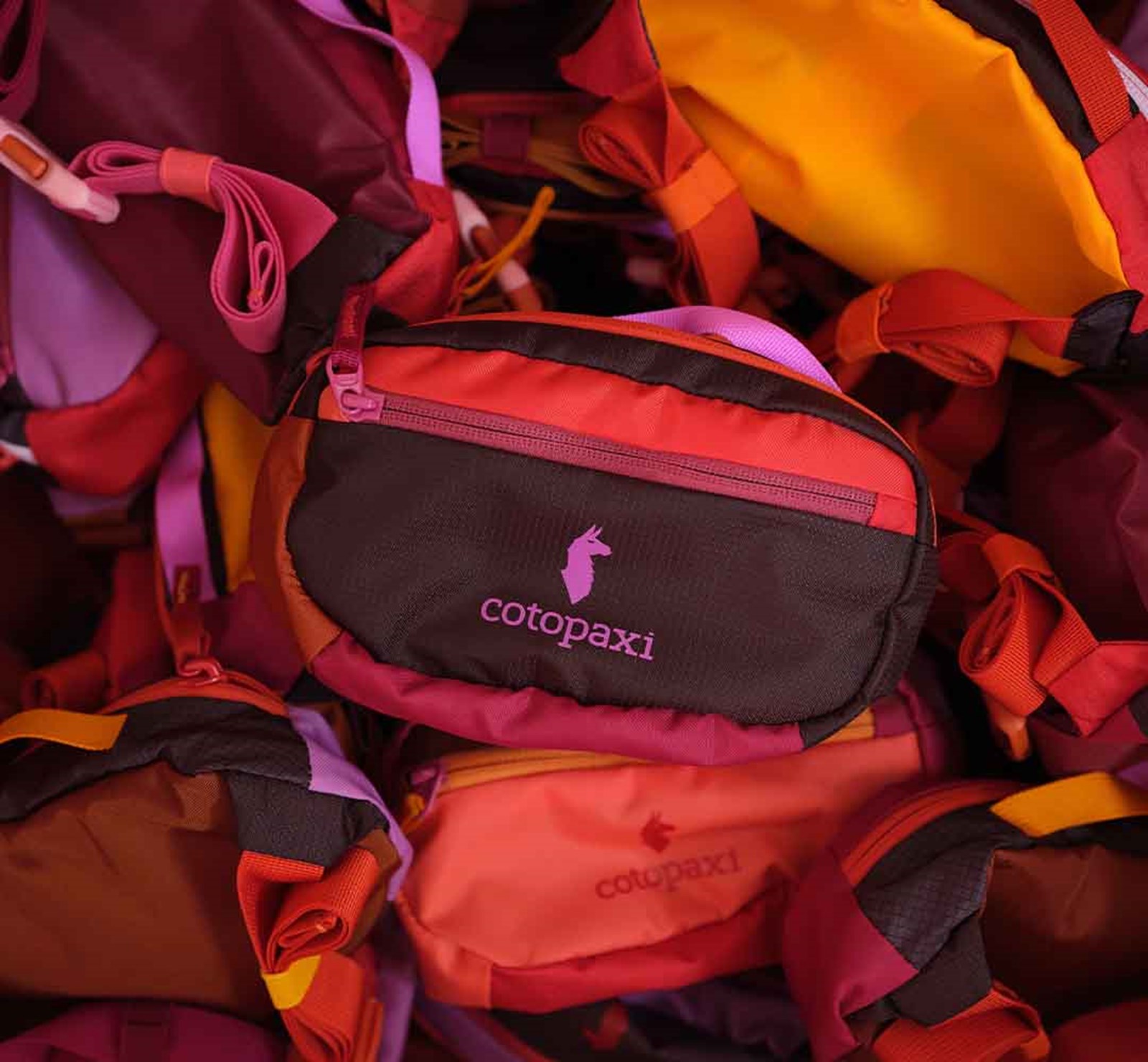 Cotopaxi bæltetasker i forskellige nuancer af rød lavet af deadstock materialer.