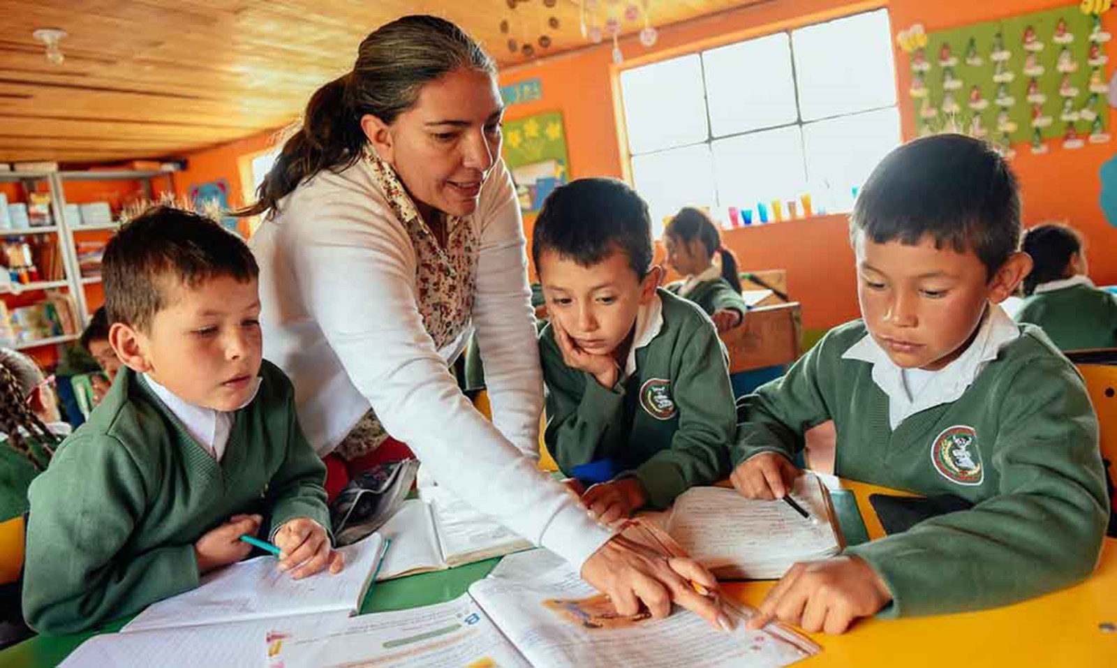 En kvinde underviser tre børn i en nyopført skole i Latinamerika.