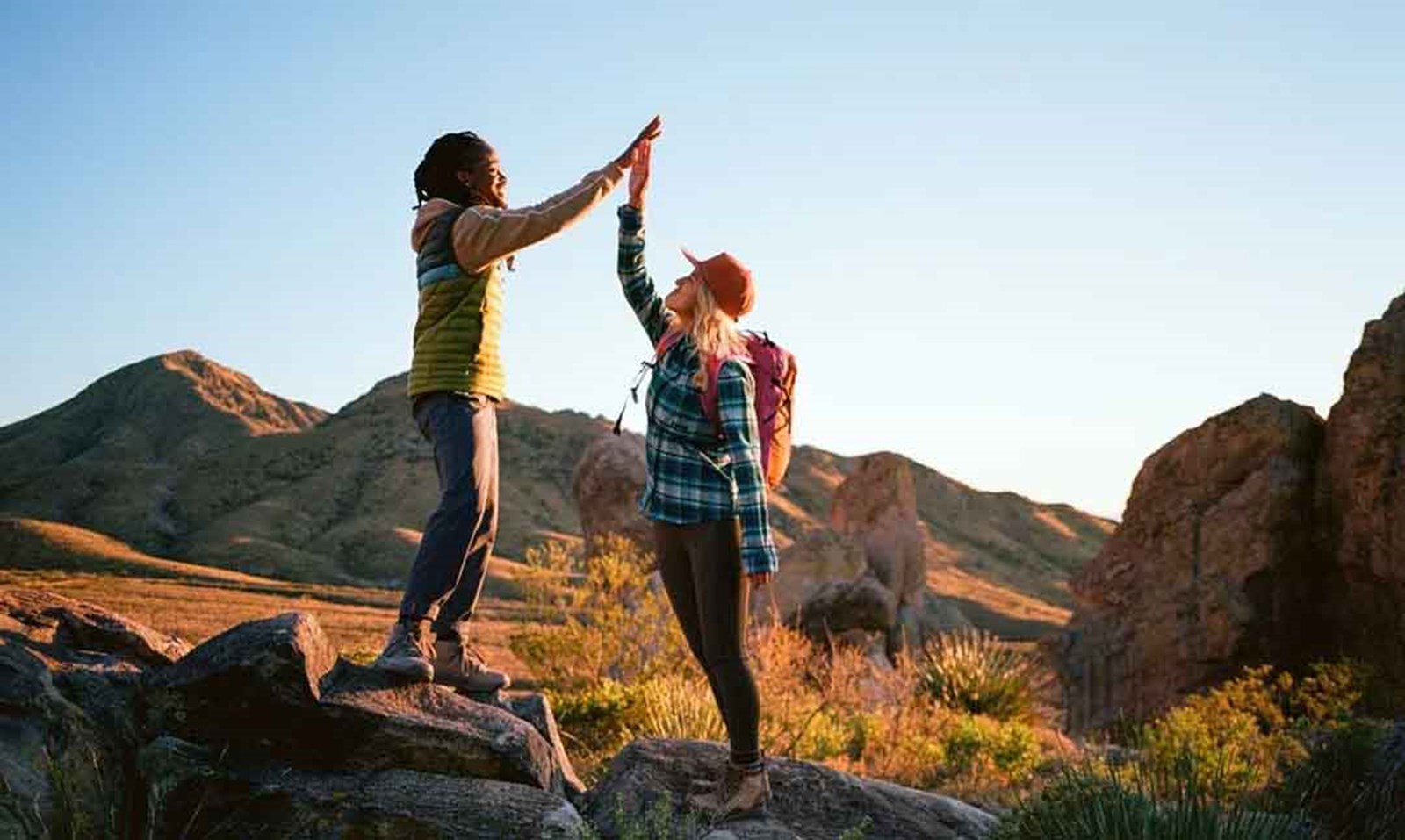 To mennesker iført cotopaxi tøj der giver hinanden en high five i en ørken