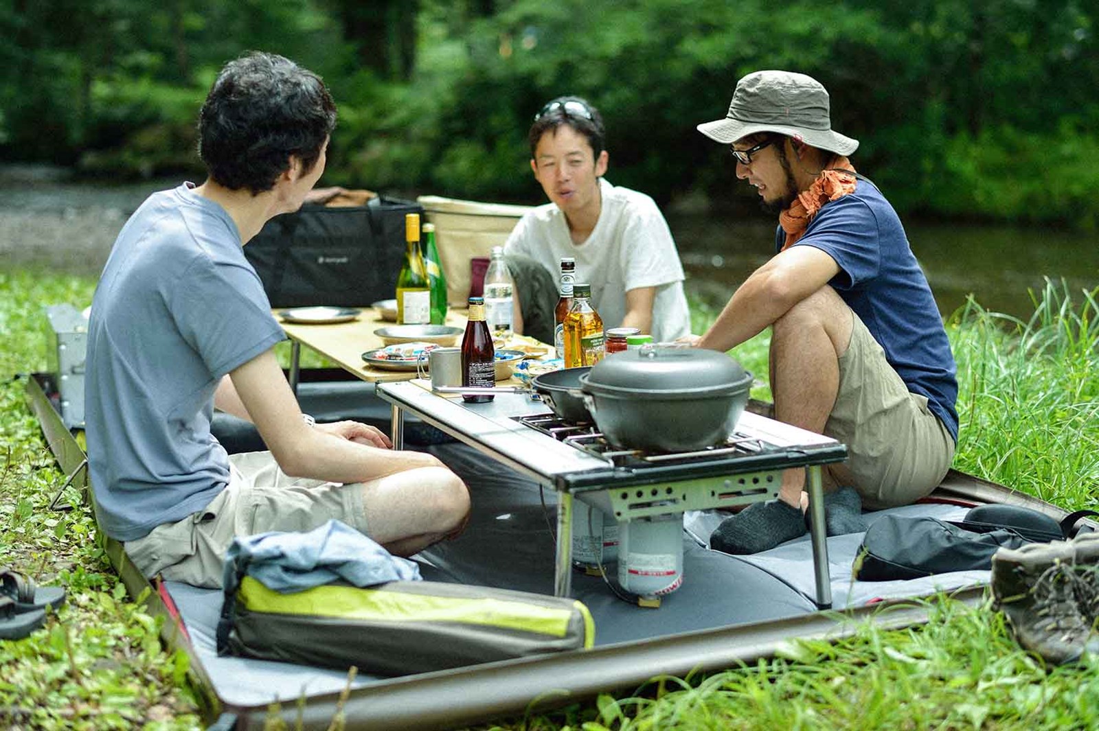Tre mennesker der hygger sig omkring lave IGT borde og laver mad i det fri.