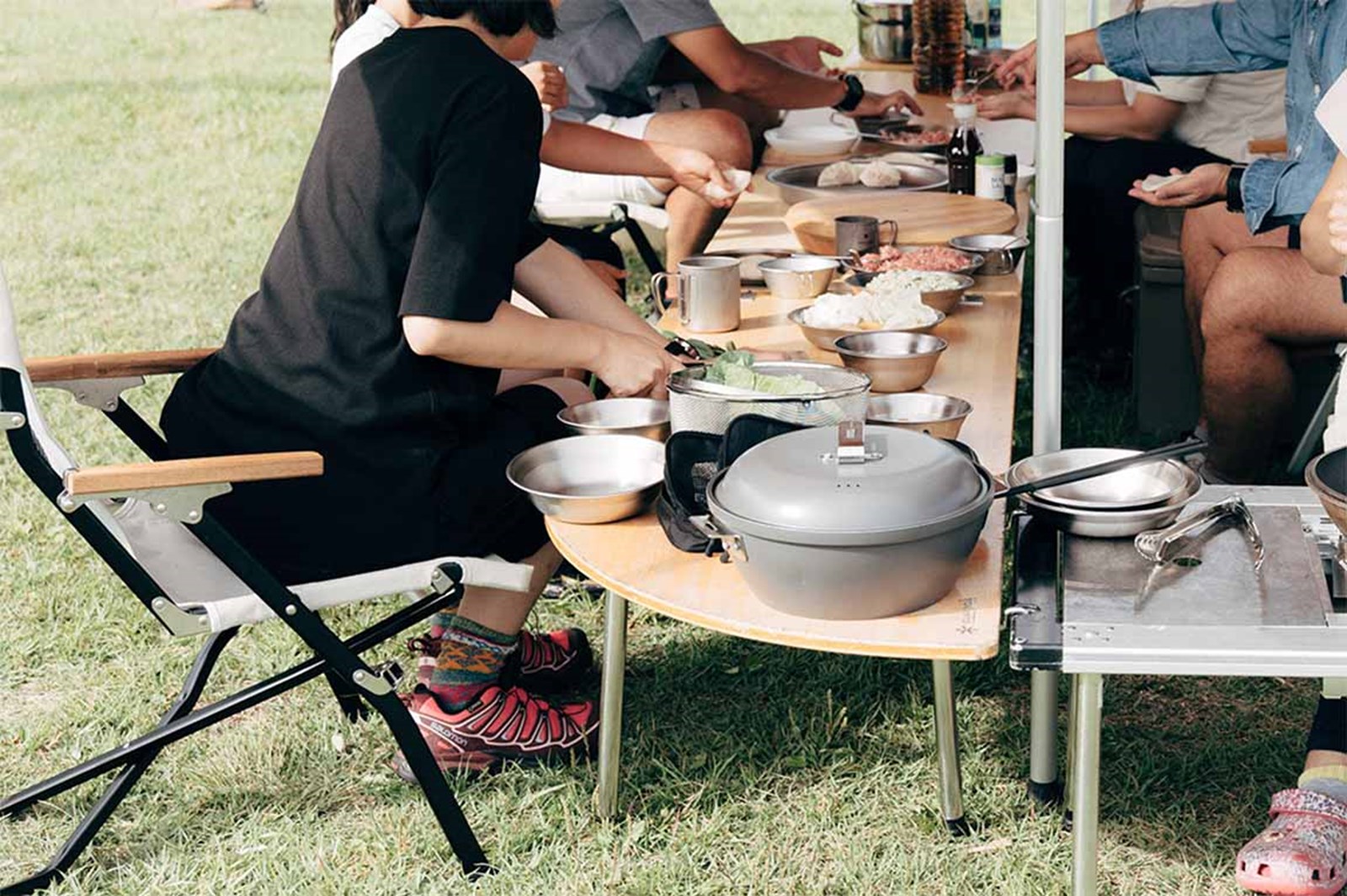En flok mennesker sidder og spiser sammen udenfor ved et lavt IGT bord med afrundede hjørner.