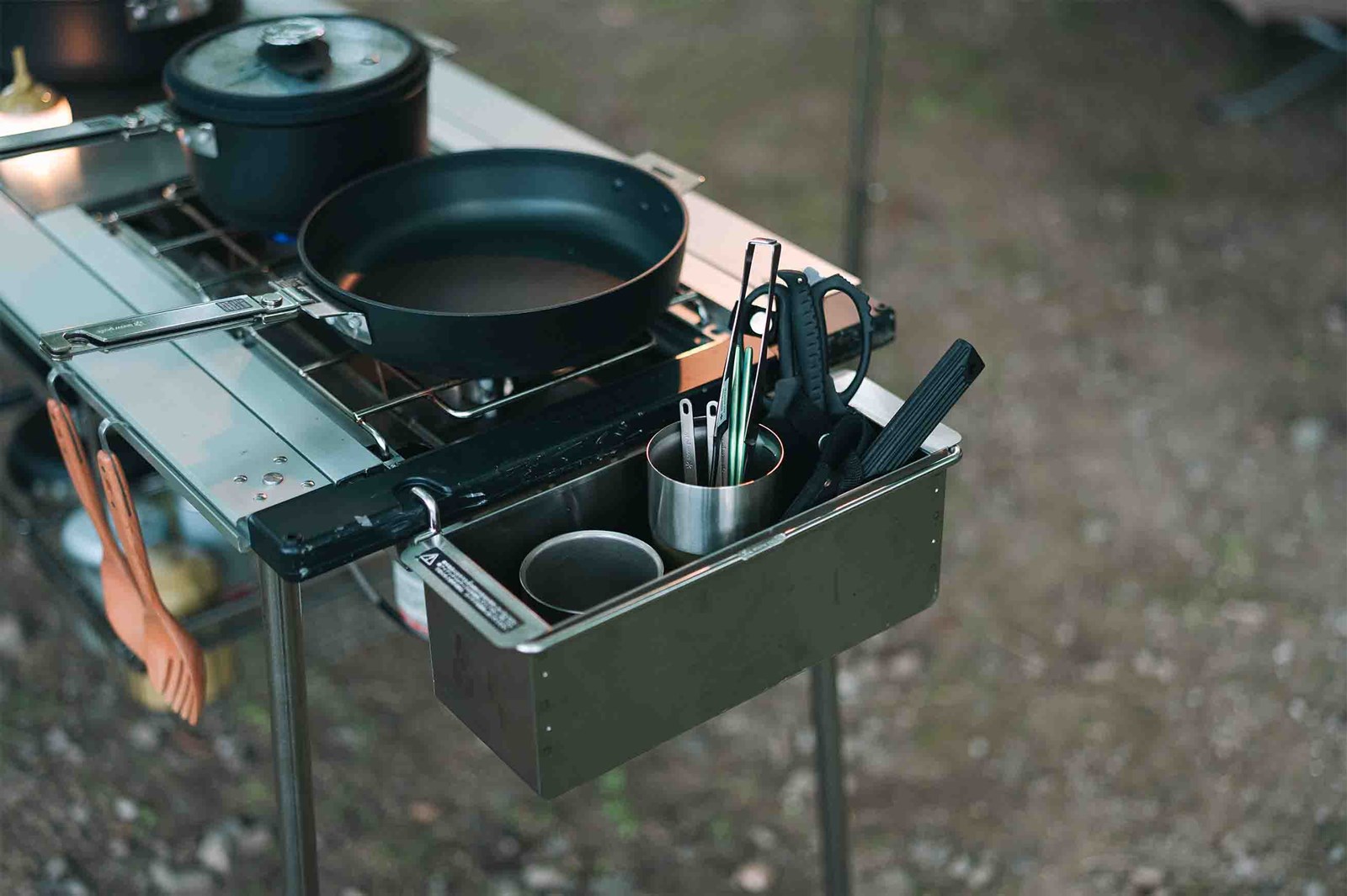 Et IGT bord udenfor med kogeplader og en stål opbevaringsboks på siden.