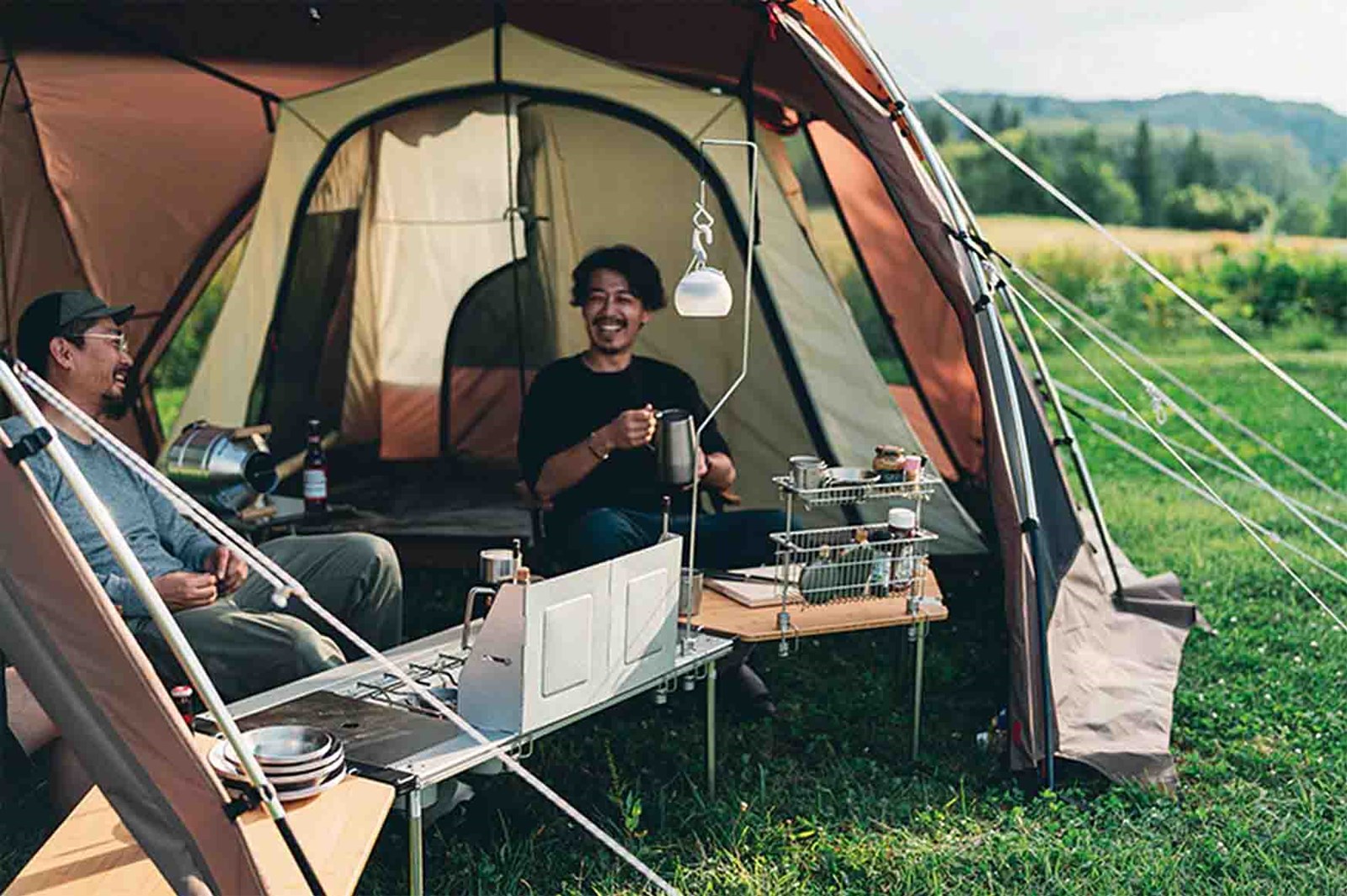 To mænd der hygger sig i et Snow Peak telt, med et modificeret og forlænget IGT bord, med både kogeplade, TTA hylder og en vindskærm.