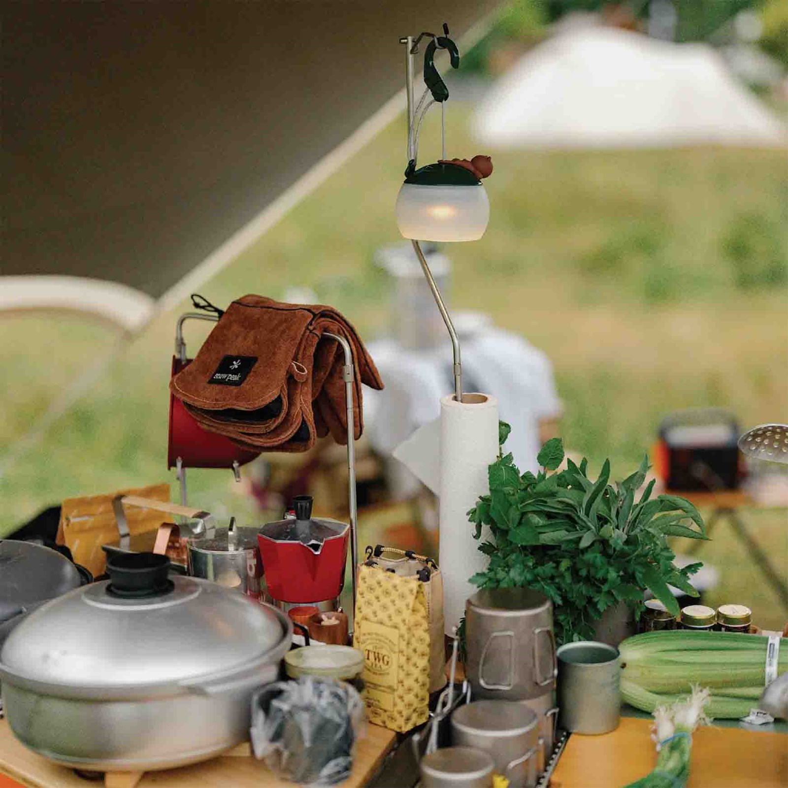 Et bord med madlavningsgrej og ingredienser, samt en lanterne holder med en køkkenrulle sat på.