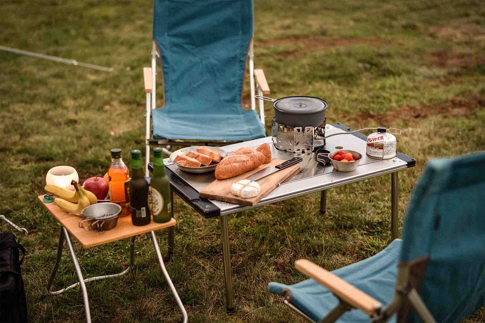 Et lavt IGT bord med mad og en lille brænder, der står udenfor med to stole.