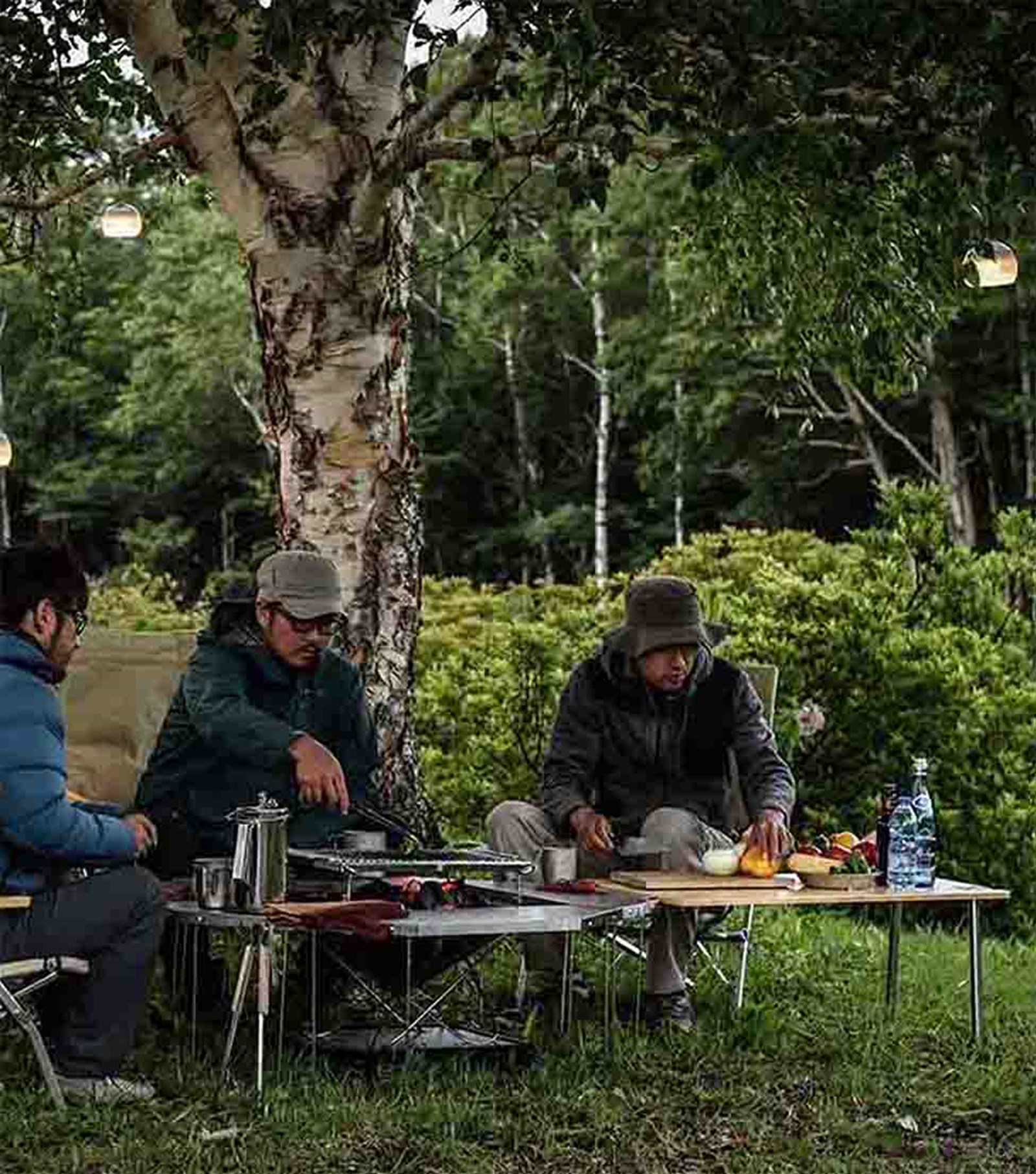 Mennesker der sidder rundt om en Jikaro Firering og laver mad på et Takibi bålfad i midten, og så er Jikaroen forlænget med en IGT bordplade.