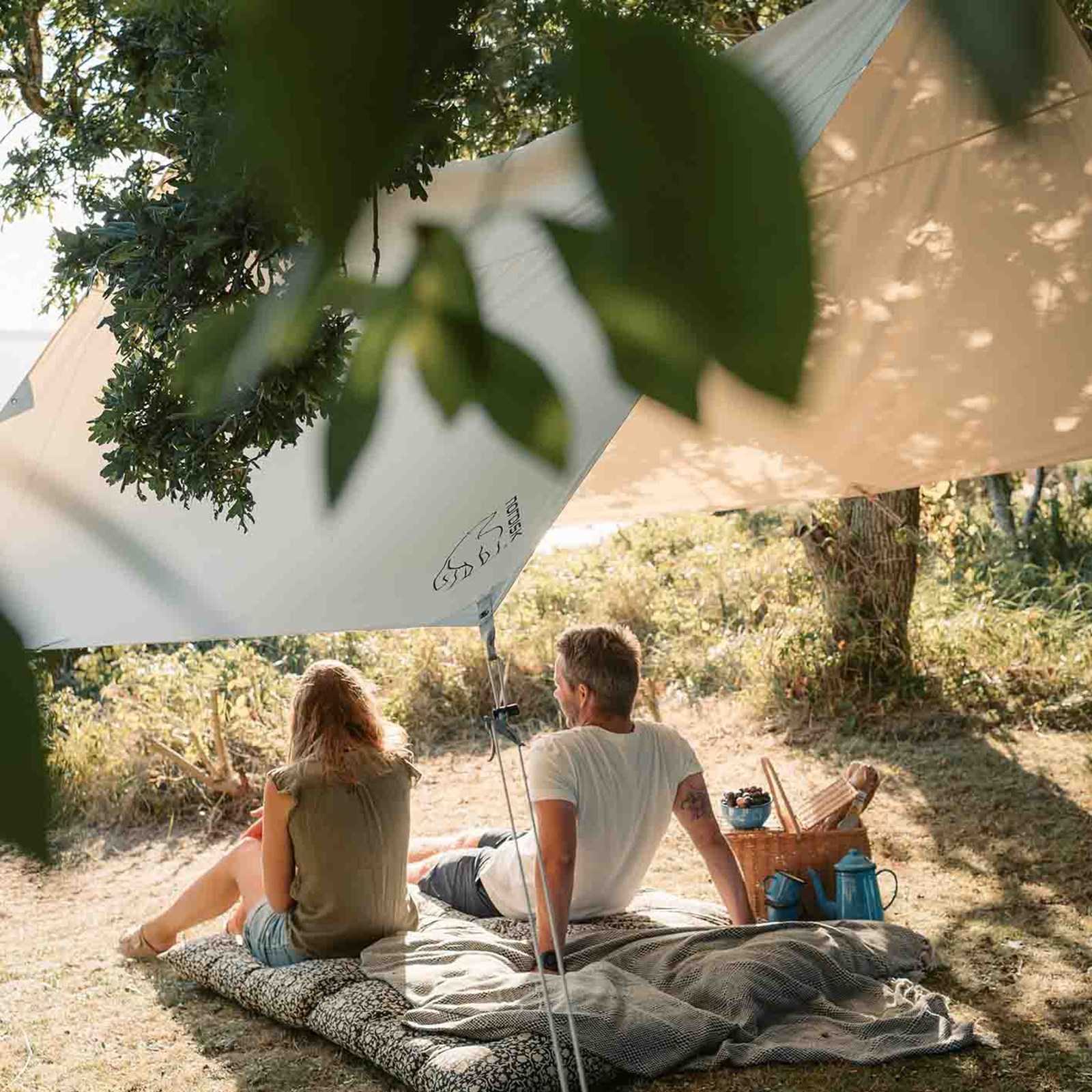 Et par der sidder og har en picnic under en tarp fra Nordisk.