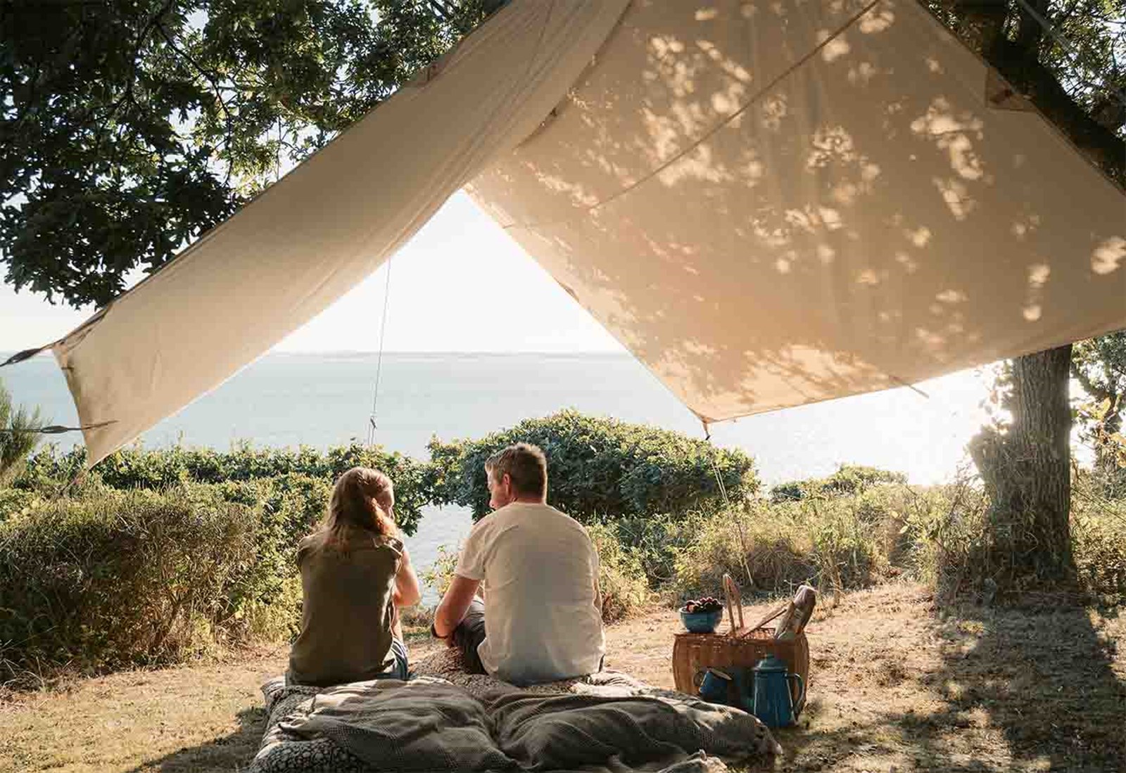 et par der sidder under en tarp med en picnic