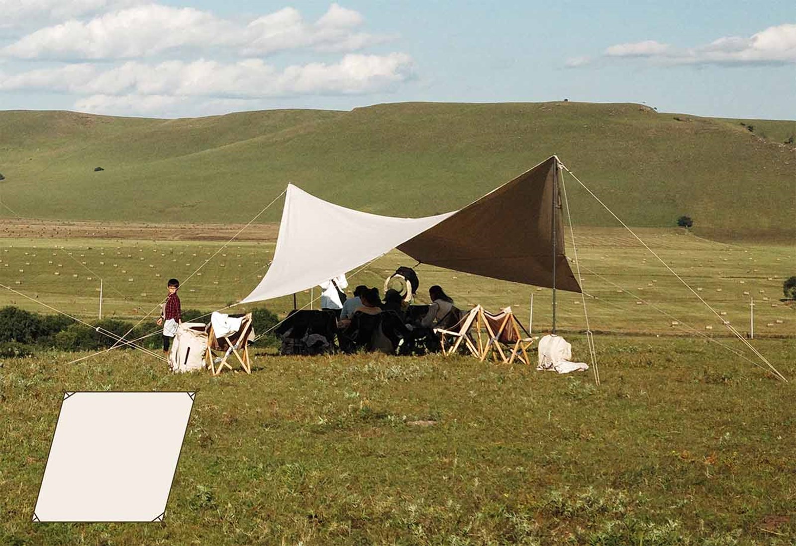 En tarp sat op på en mark, med mennesker der sidder under den.