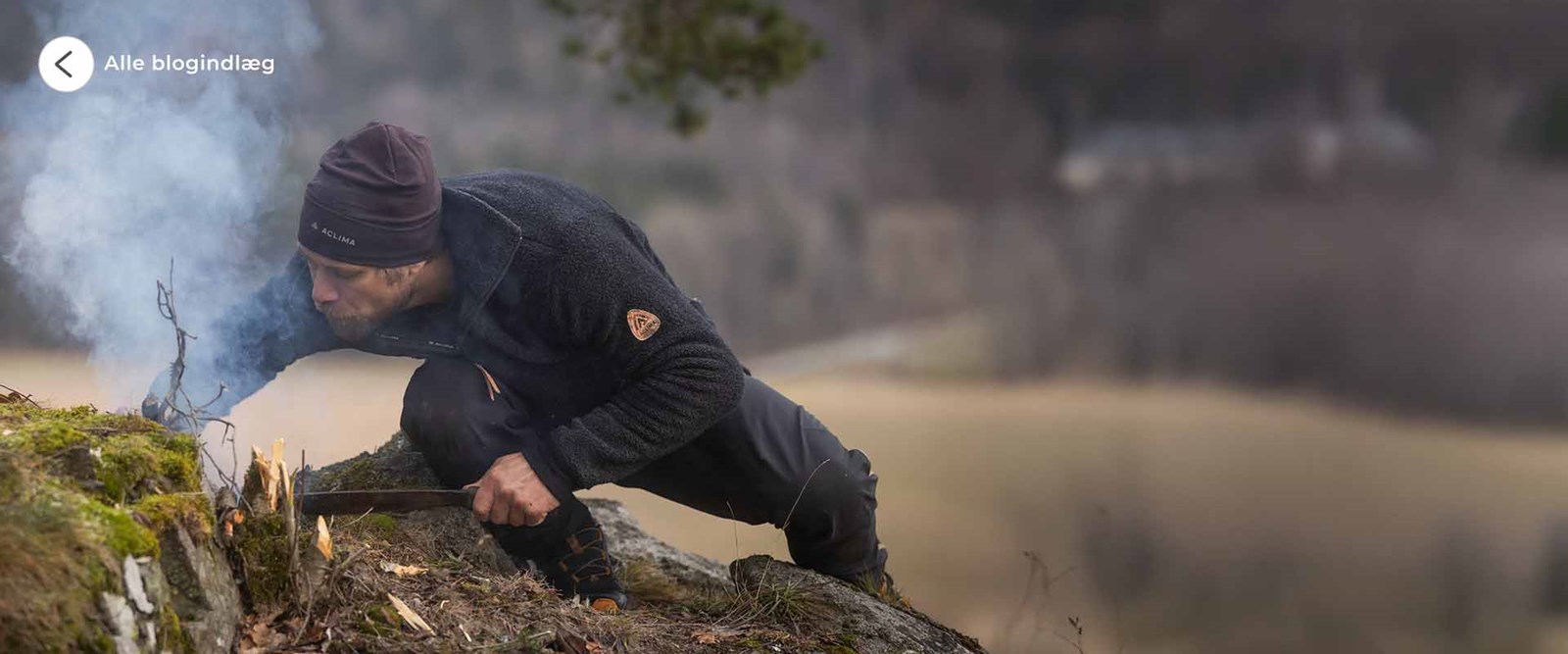 En man i Aclima beklædning, der er ved at starte et bål.