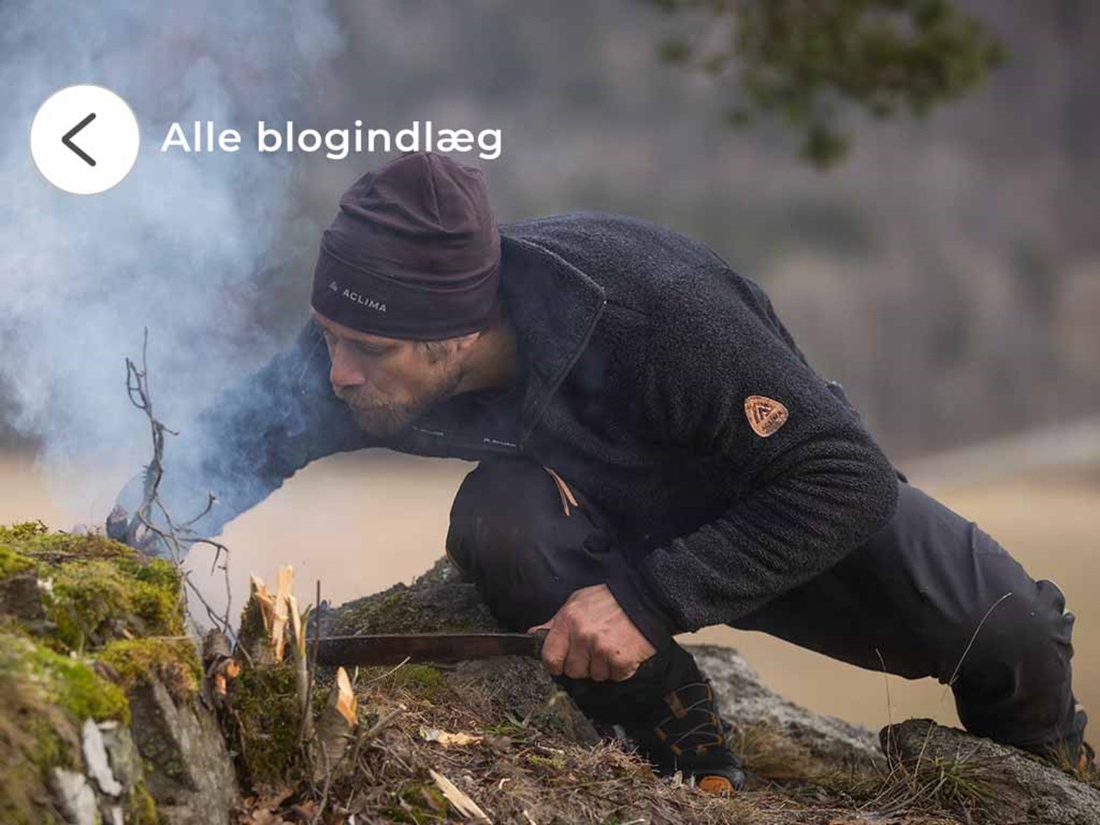 En man i Aclima beklædning, der er ved at starte et bål.