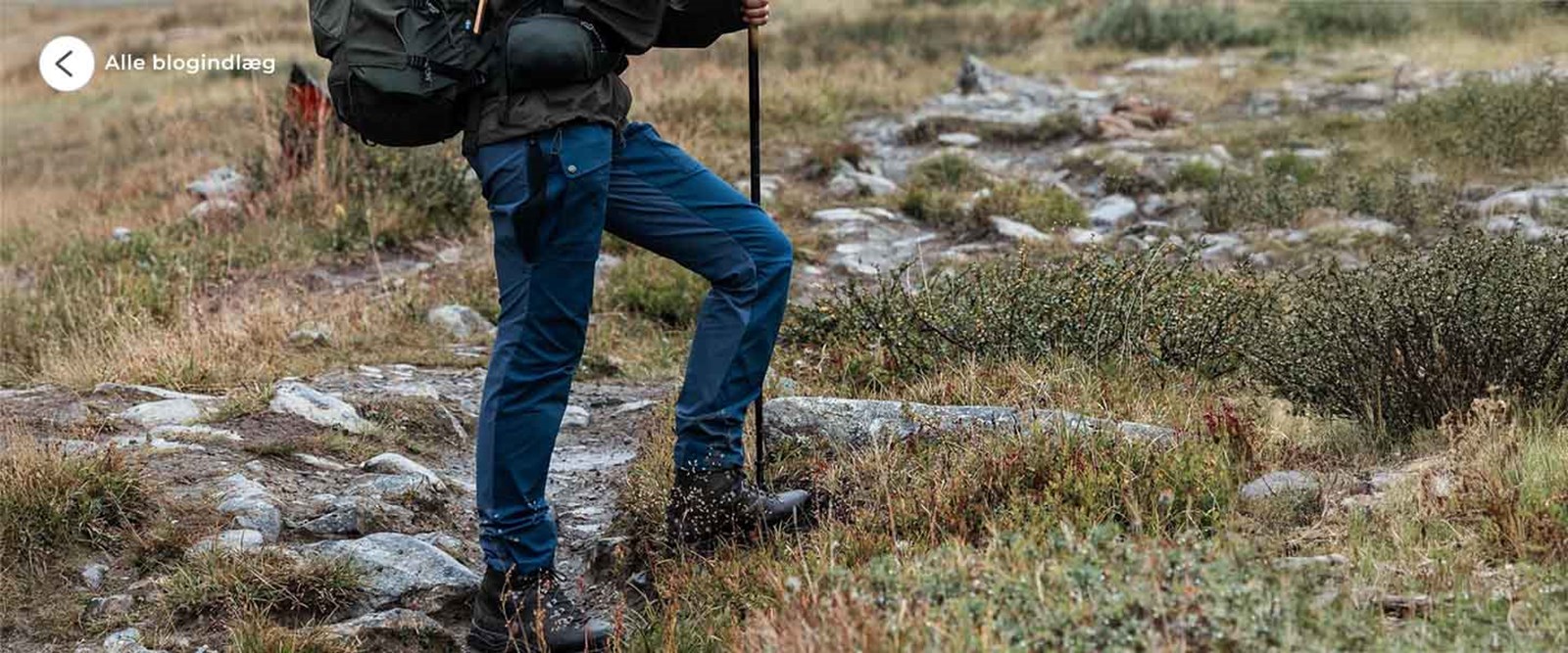 kvinde i fjeldet med blå vandrebukser og støvler på.