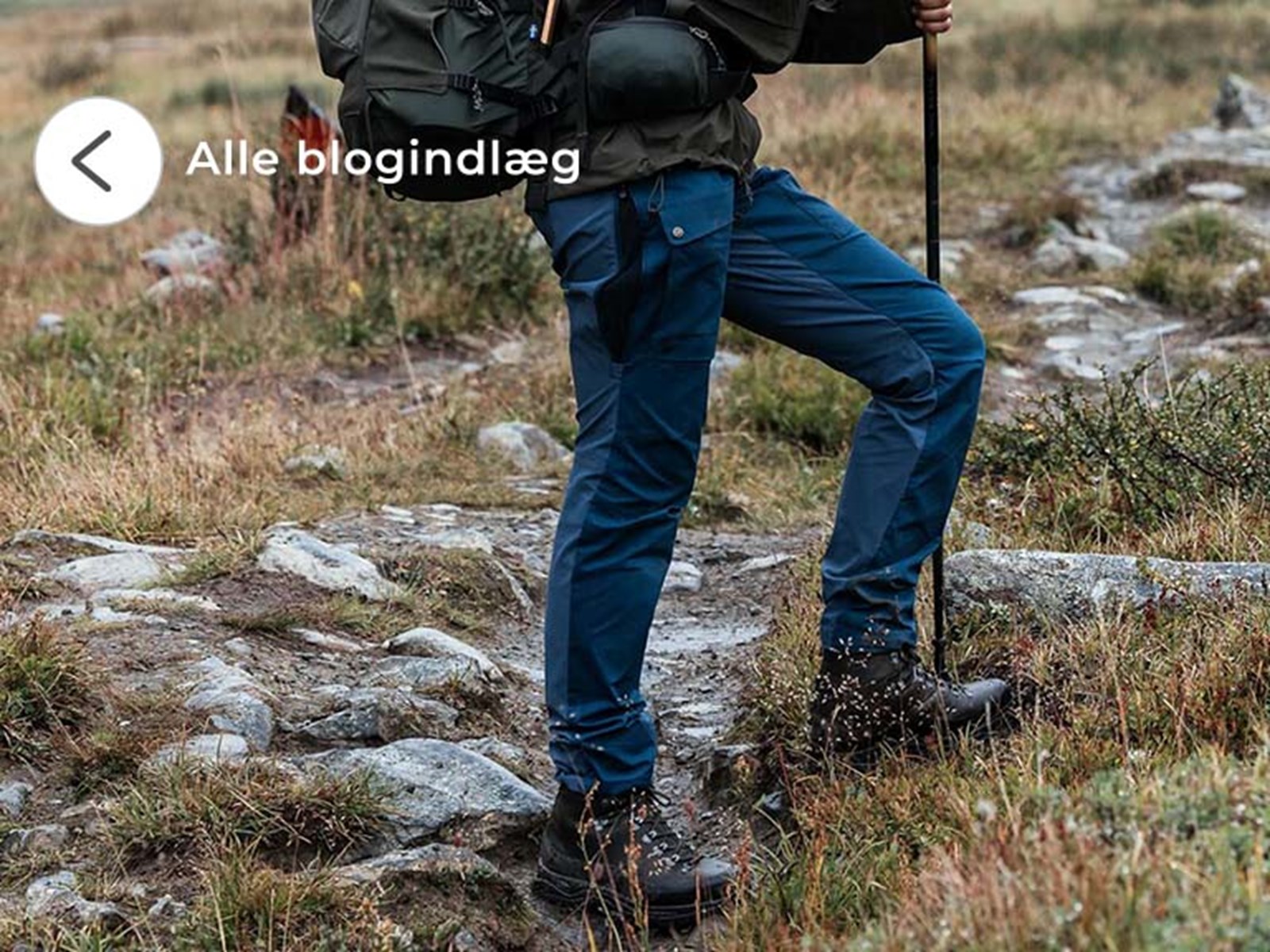 kvinde i fjeldet med blå vandrebukser og støvler på.