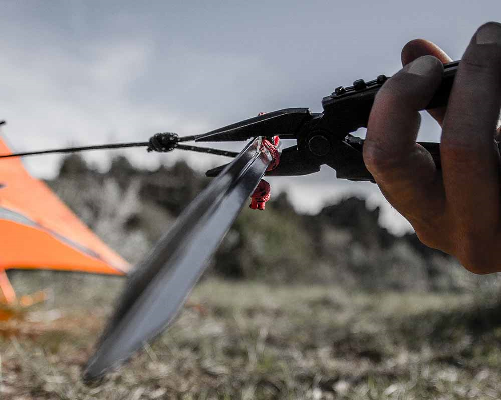 Mand bruger multitool til at fikse et telt