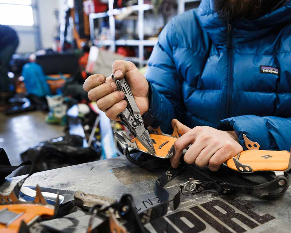 Mand bruger multitool til at fikse snesko