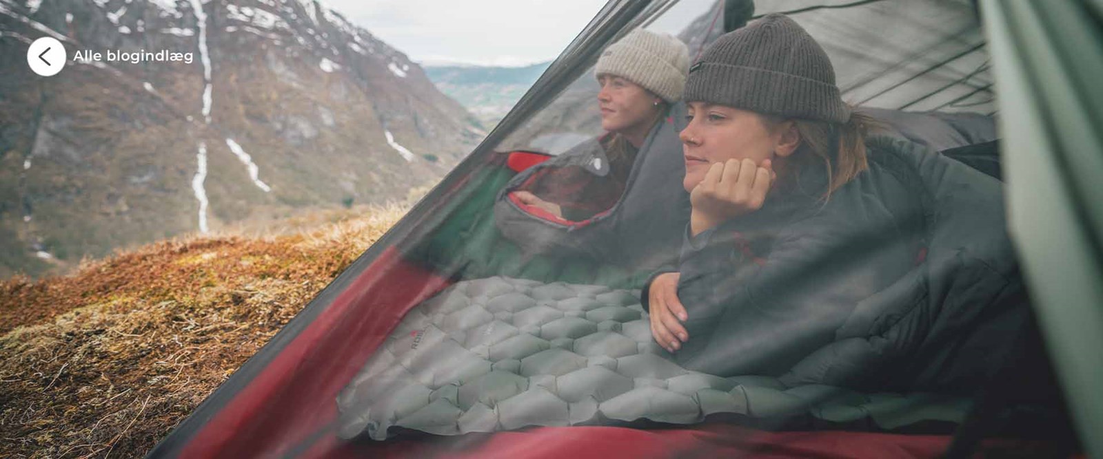 To kvinder i en telt der kigger ud over horisonten.