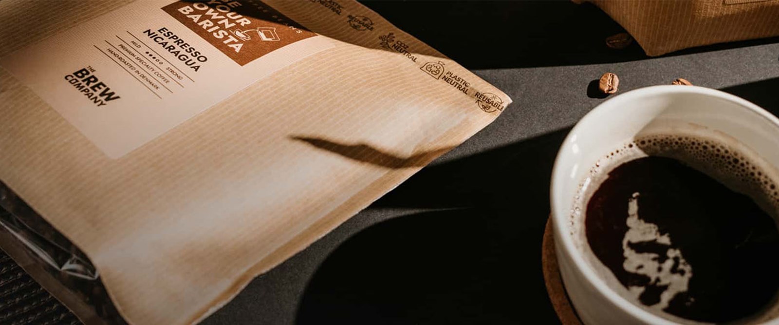 Close up af The Brew Company kaffepose og en kop kaffe.