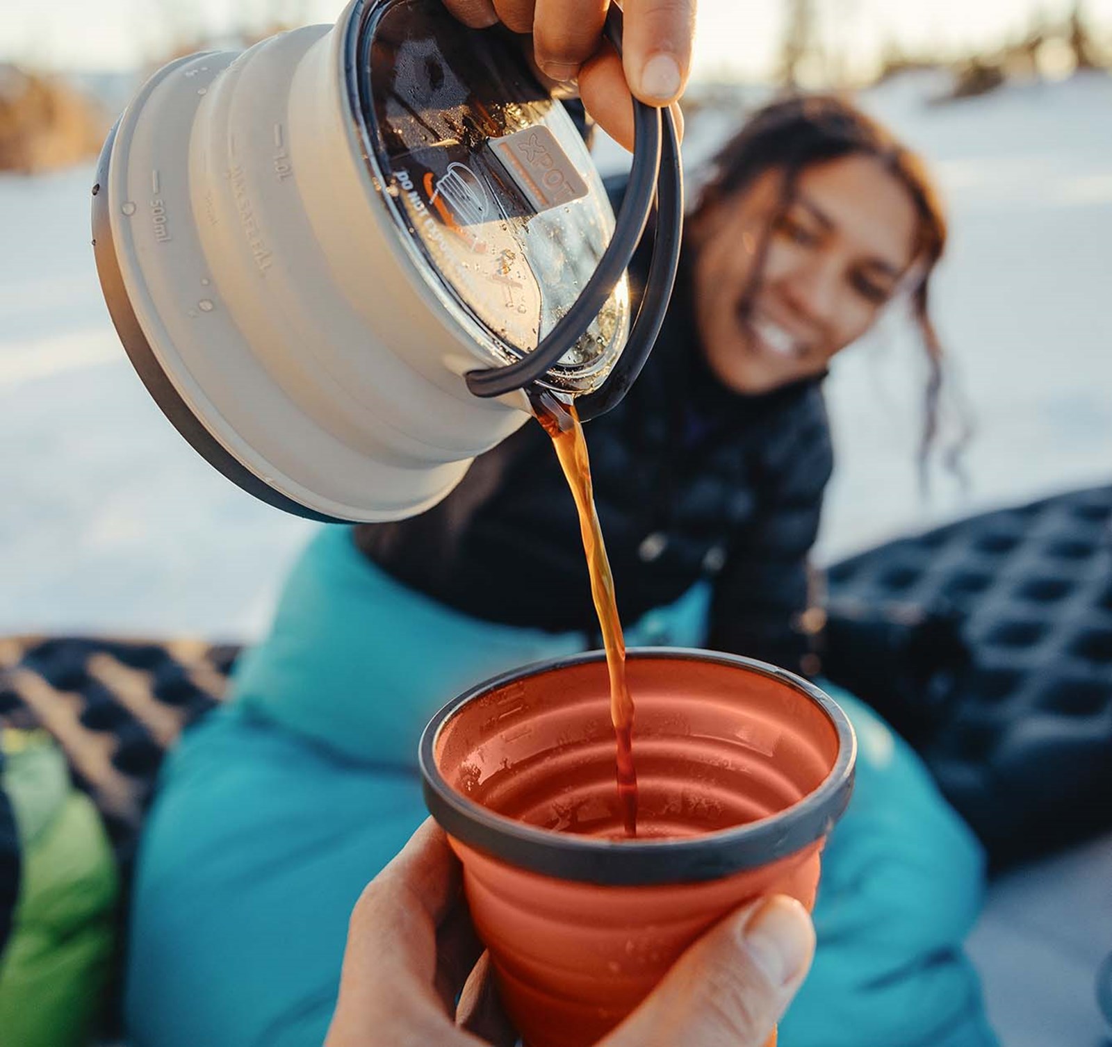 En kvinde hælder fakke op fra en kedel fra Sea To Summit.