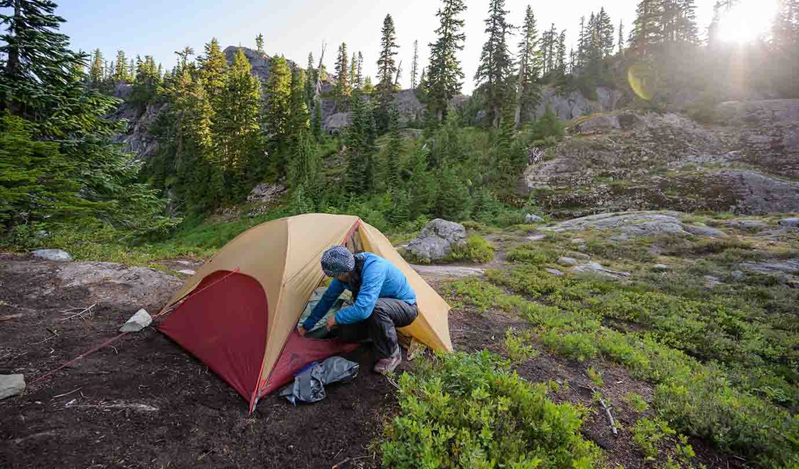En person der sætter et kuppeltelt op i skoven.
