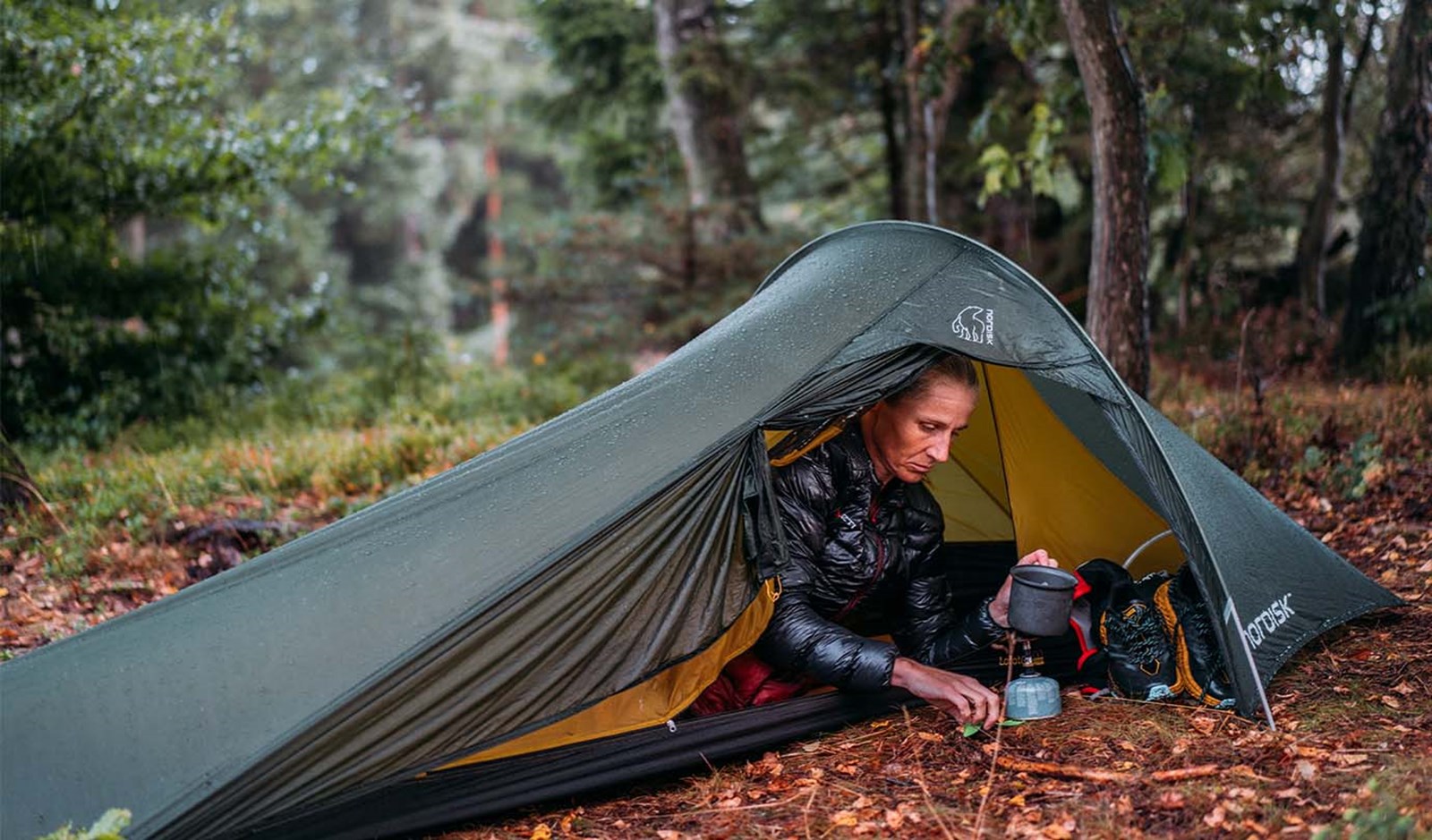 En kvinde i et tunneltelt, der varmer vand i sin apsis.