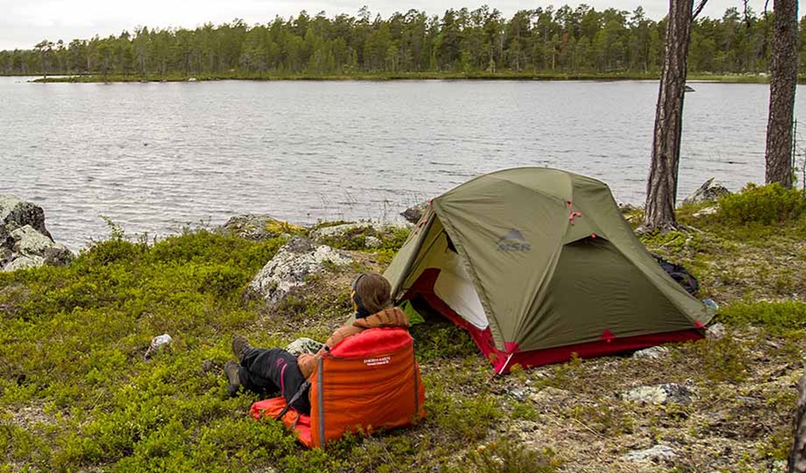 En person skuer ud over vandet ved siden af sit MSR telt.