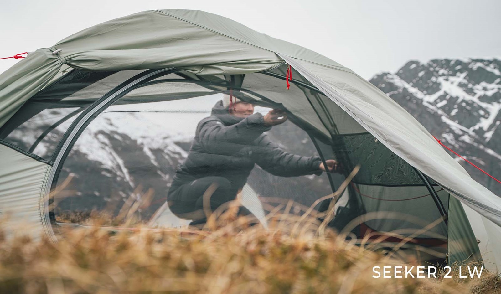 Kvinde lukker telt på toppen af et bjerg