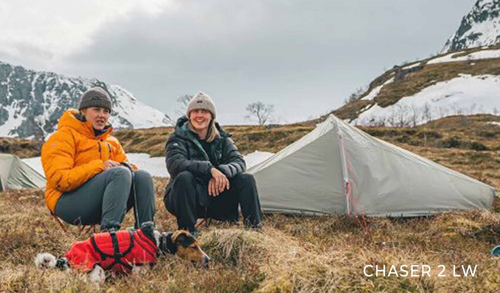 2 piger sidder foran deres telt på toppen af et bjerg