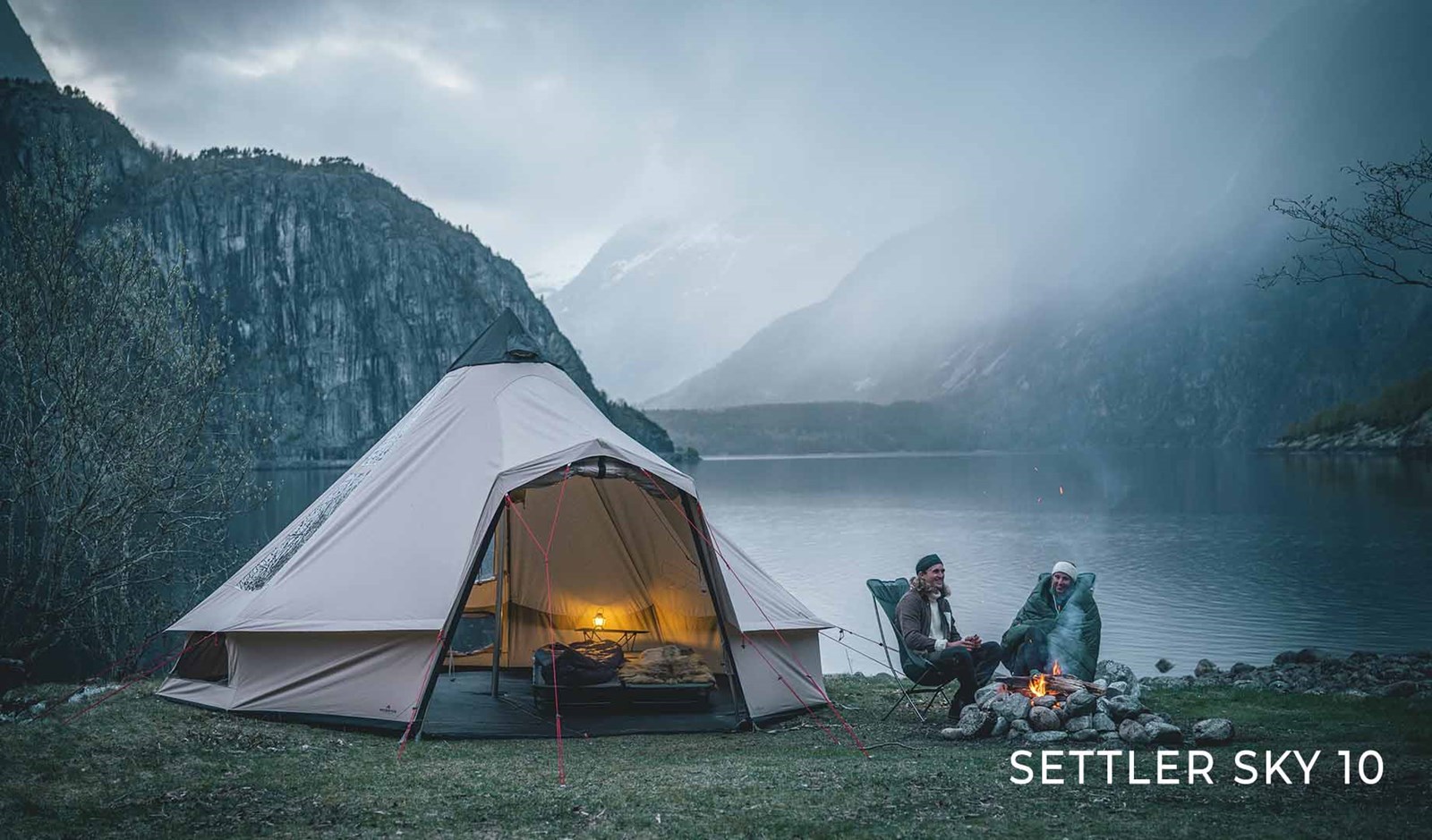 Et par der sidder udenfor deres telt ved en sø