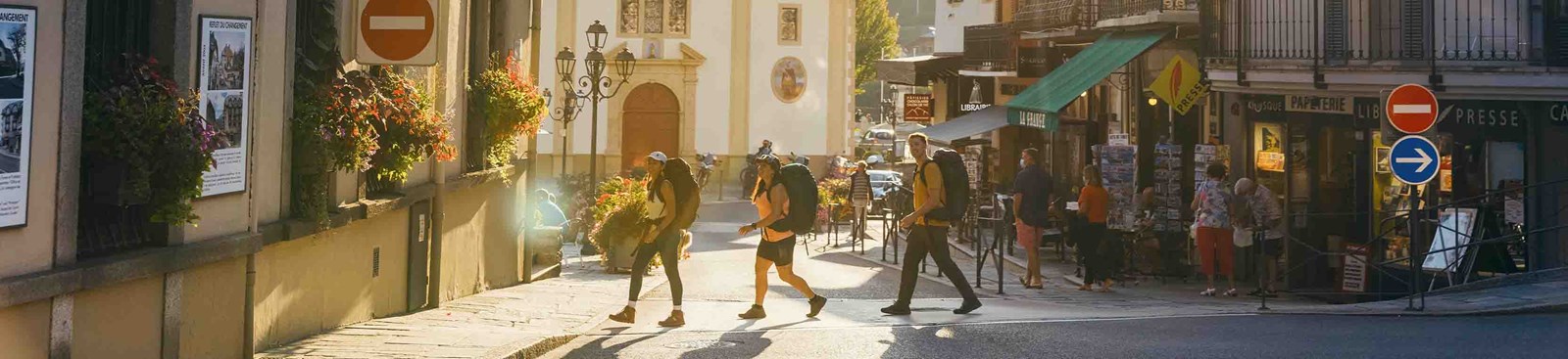 Tre backpackere der krydser en vej.