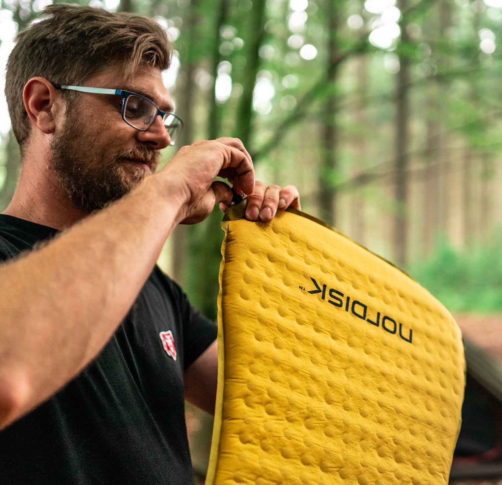 En mand der er ved at lukke luften ud af et Nordisk liggeunderlag.