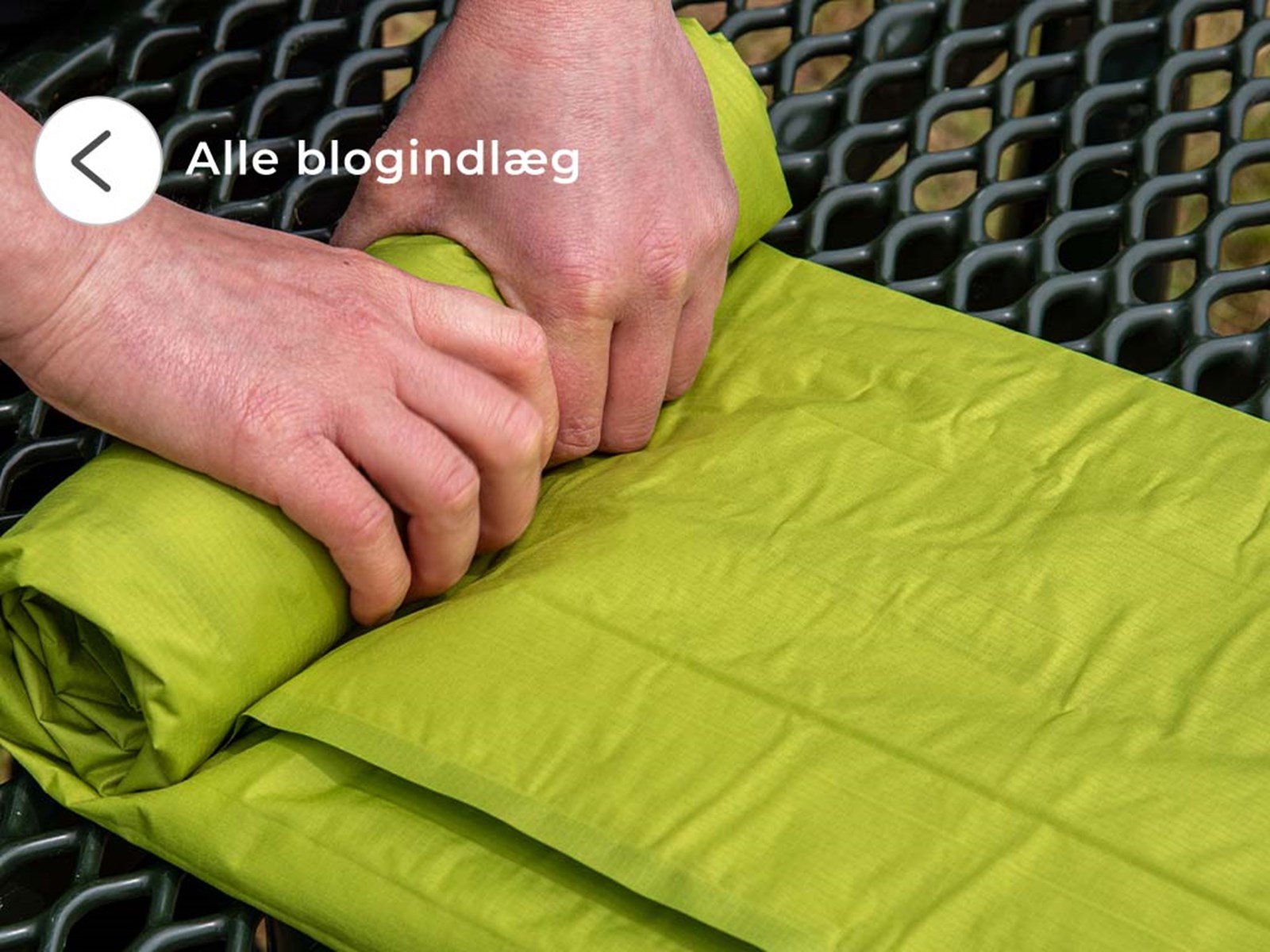 En person der ruller et liggeunderlag sammen.