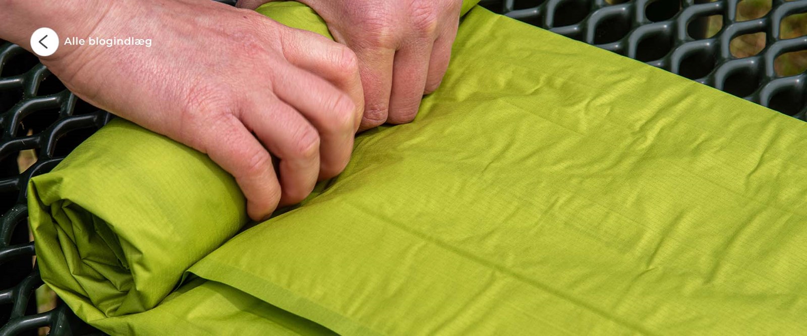 En person der ruller et liggeunderlag sammen.
