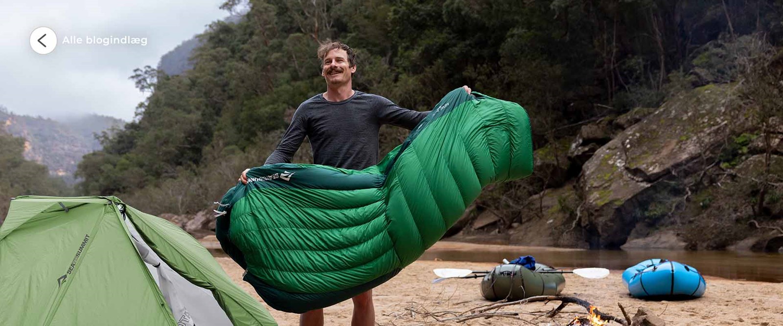 En mand lufter sin sovepose ude foran sit telt.