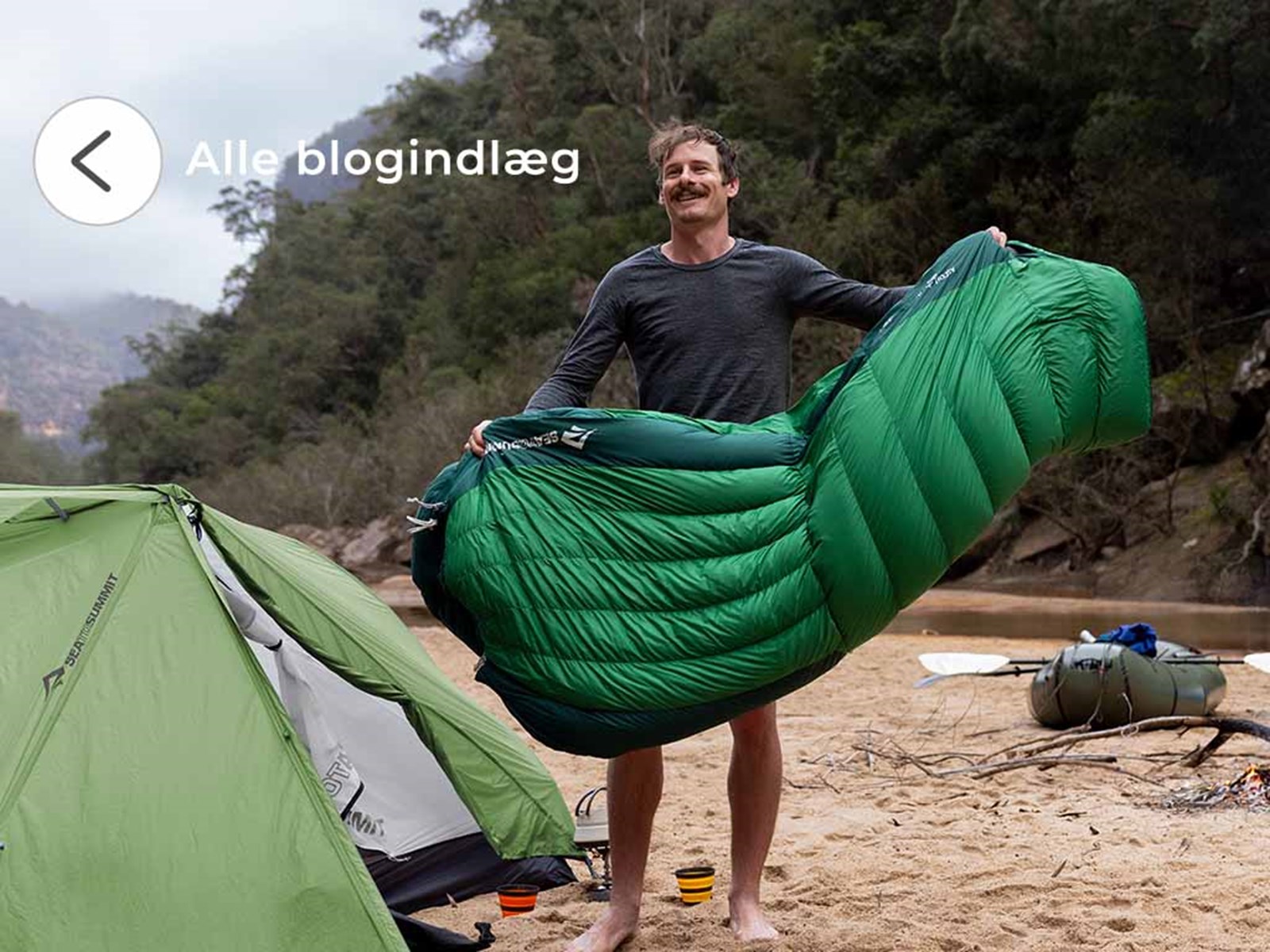 En mand lufter sin sovepose ude foran sit telt.