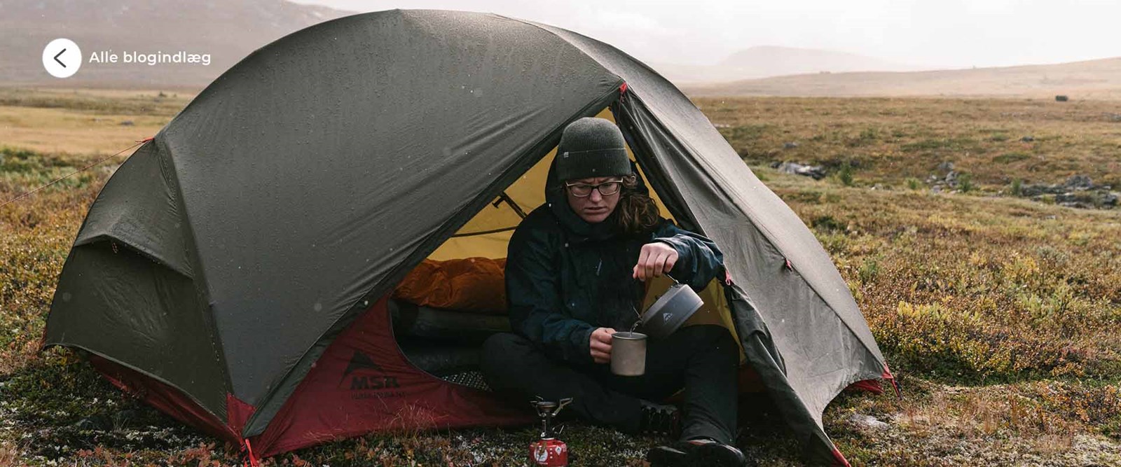Kvinde der sidder i et kuppeltelt ude i den vilde natur