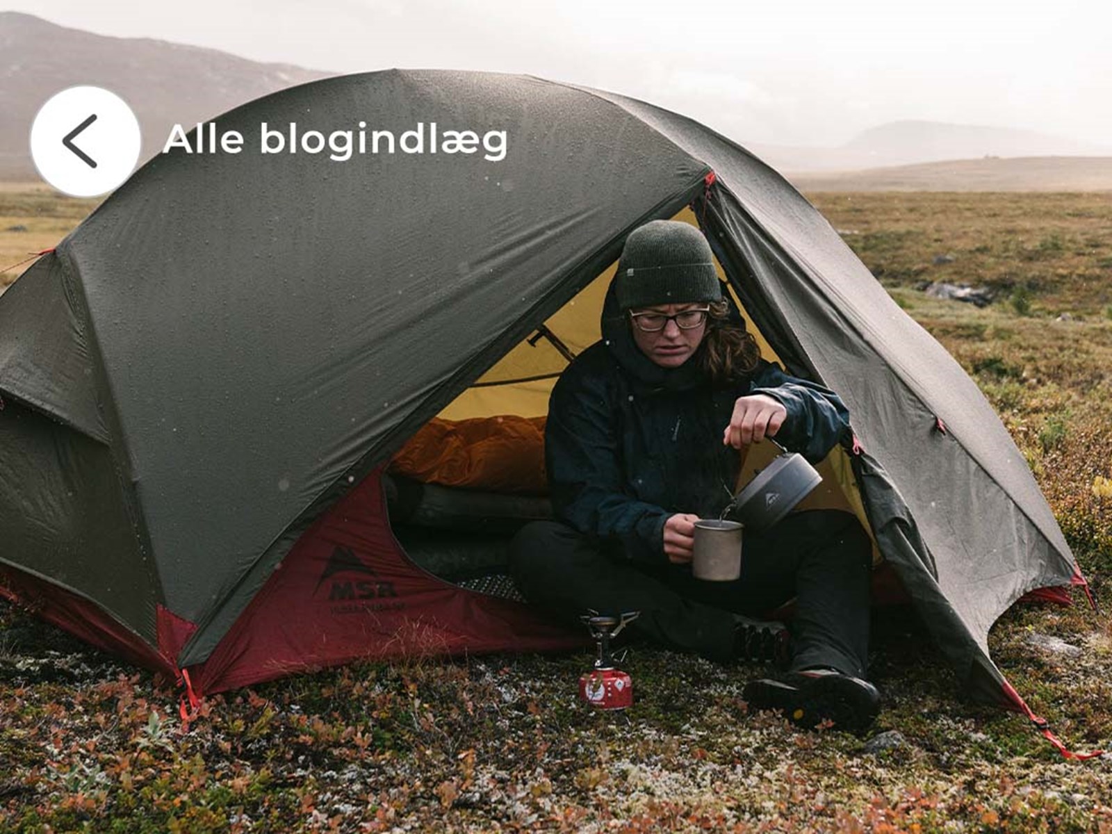 Kvinde der sidder i et kuppeltelt ude i den vilde natur