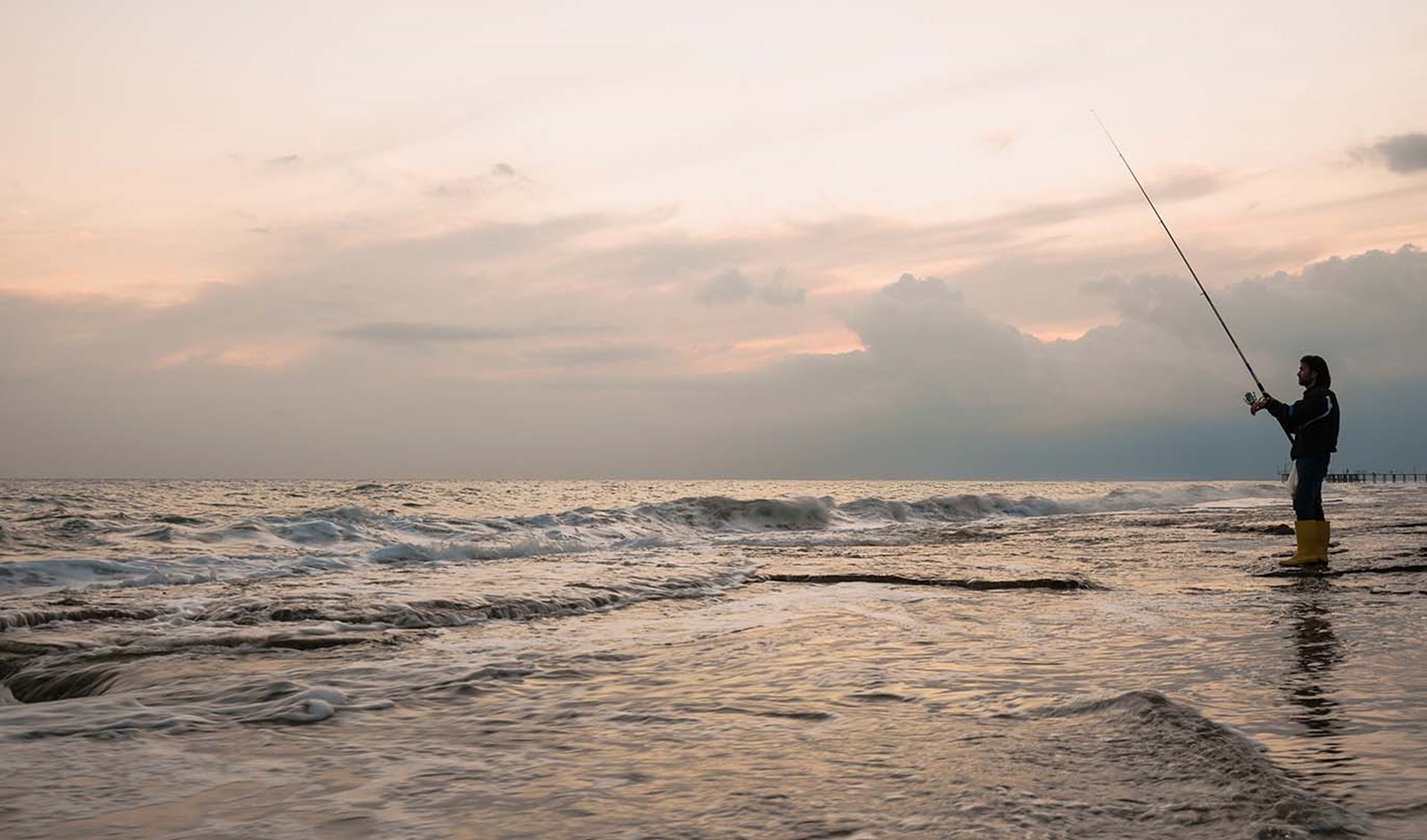 En mand der fisker ved kysten.