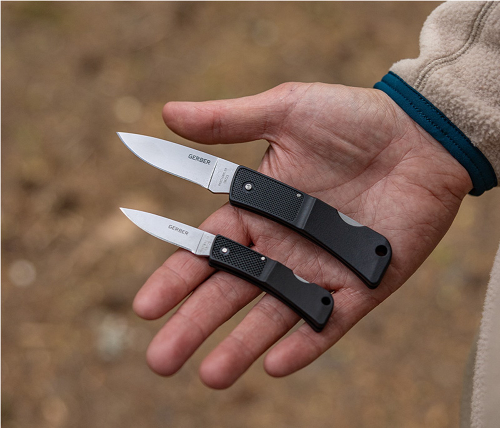 To Gerber knive i forskellige størrelser placeret i en hånd.