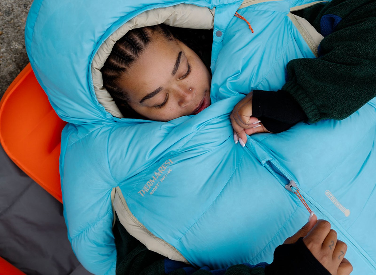 En person der ligger i en sovepose med åbninger til armene.